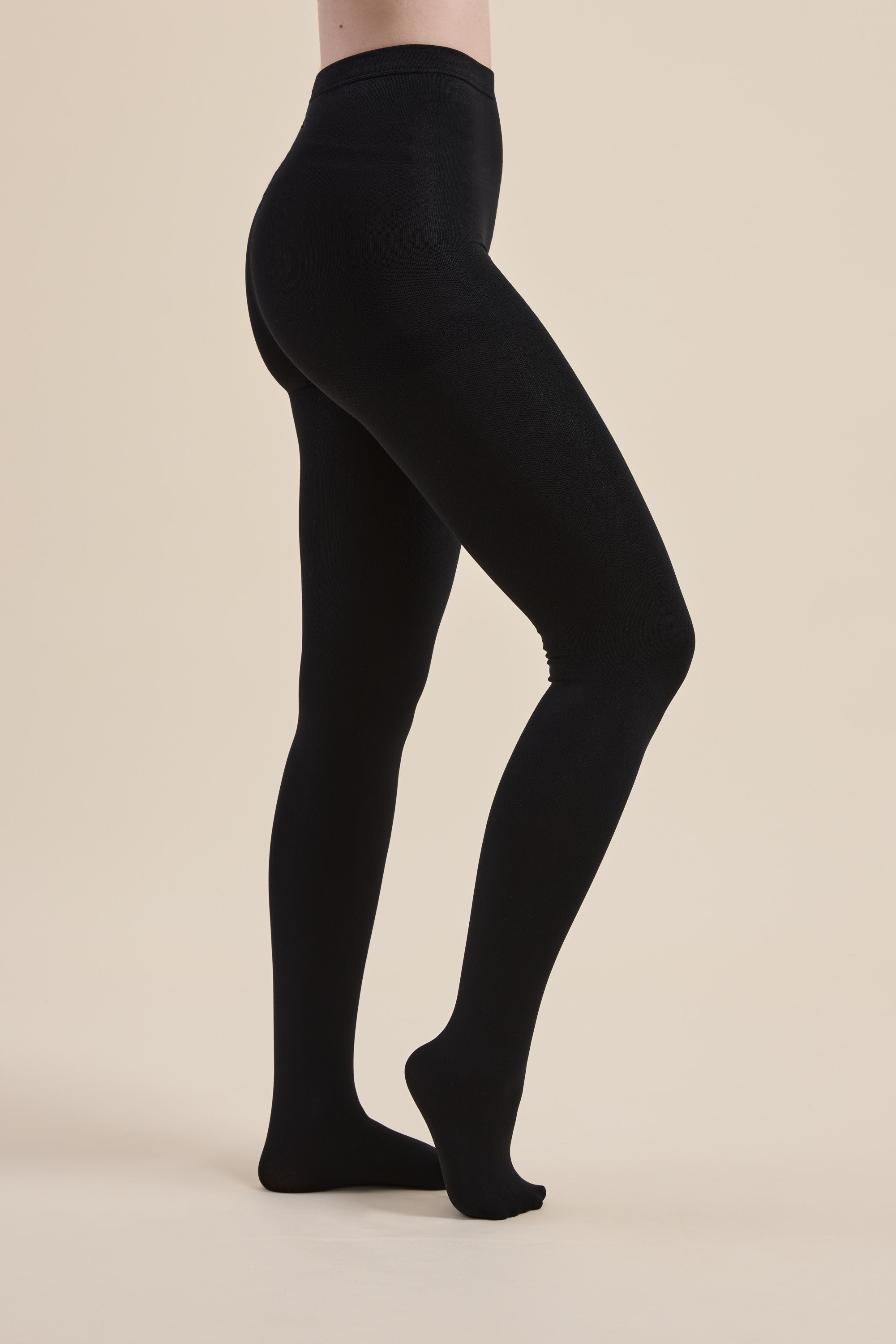 Model in Max Recycled Fleecy Tights stands on tiptoe against a plain beige background.