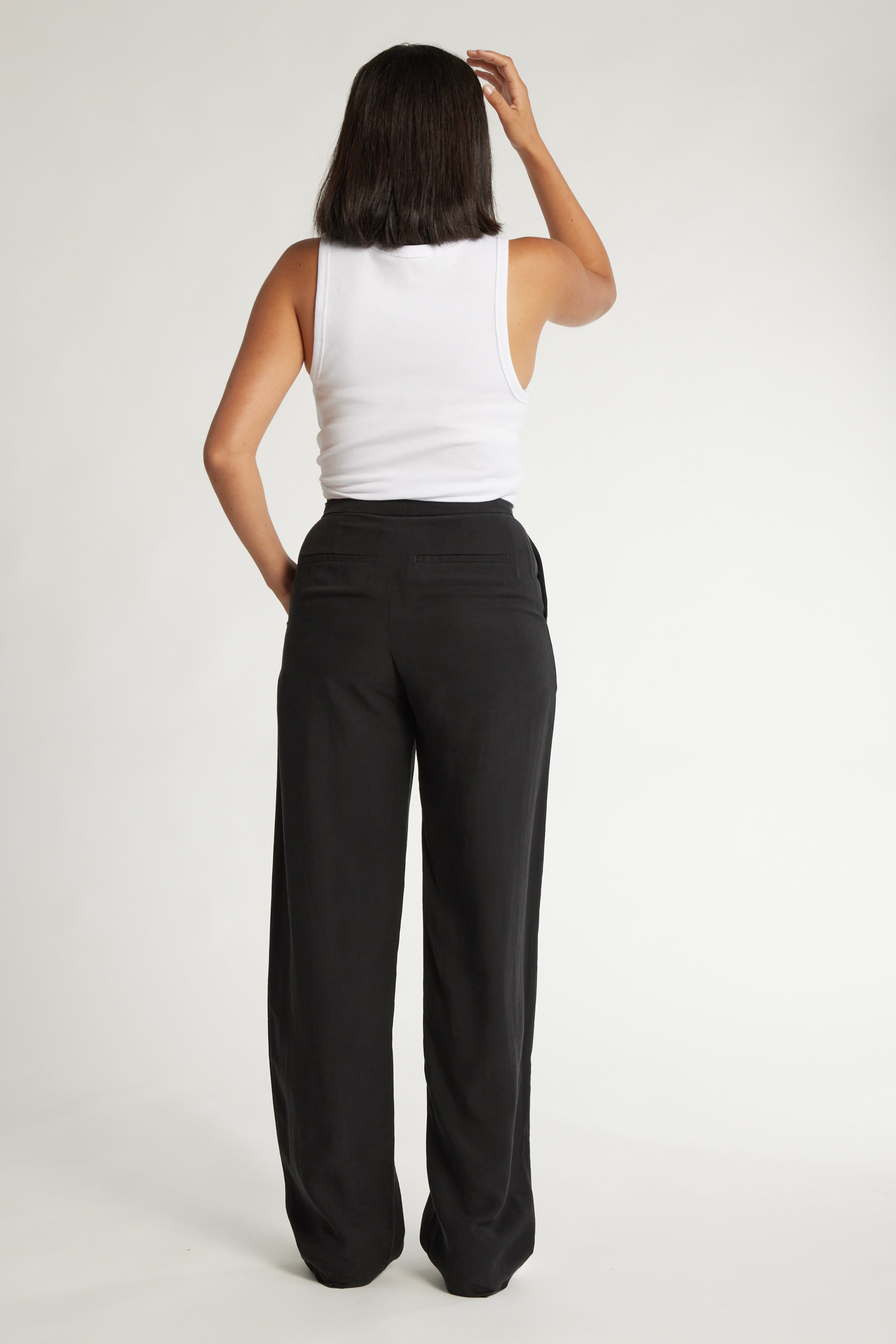 Person in a white tank top and Max's The Ultimate Wide Leg Pants made from sustainable fabrics.