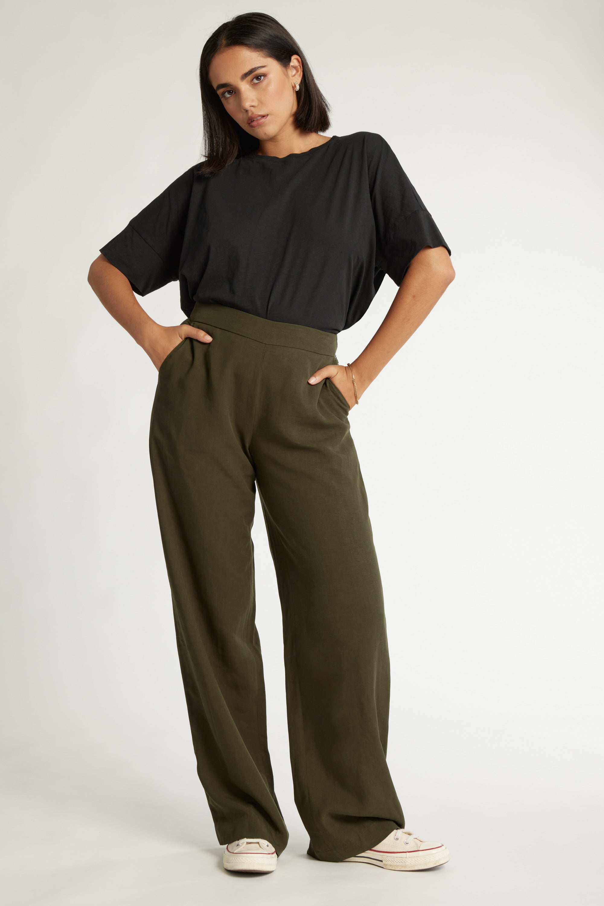 Woman in black tee and Max’s The Ultimate Wide Leg Pants stands with hands in pockets.