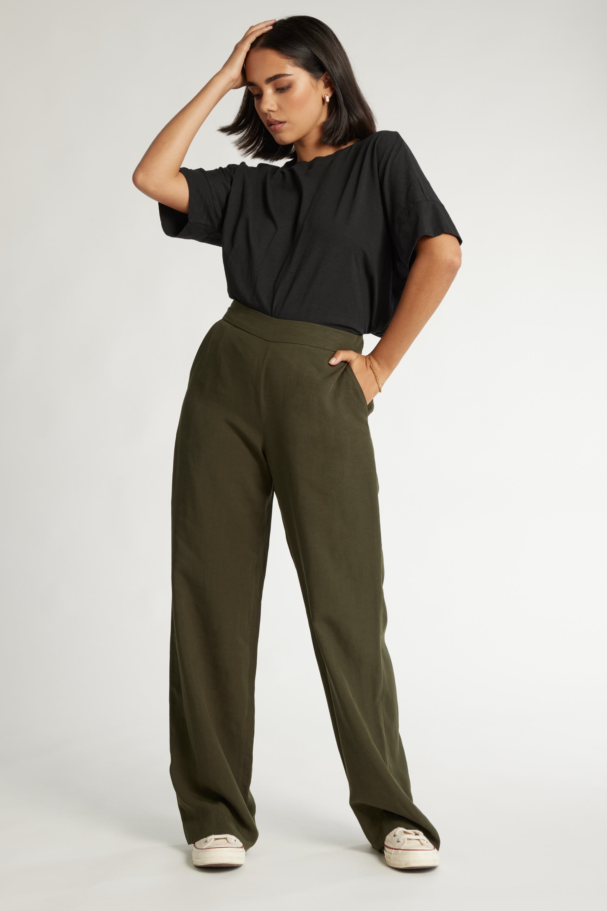 Woman in black tee and Max The Ultimate Wide Leg Pants, one hand on head, other in pocket.
