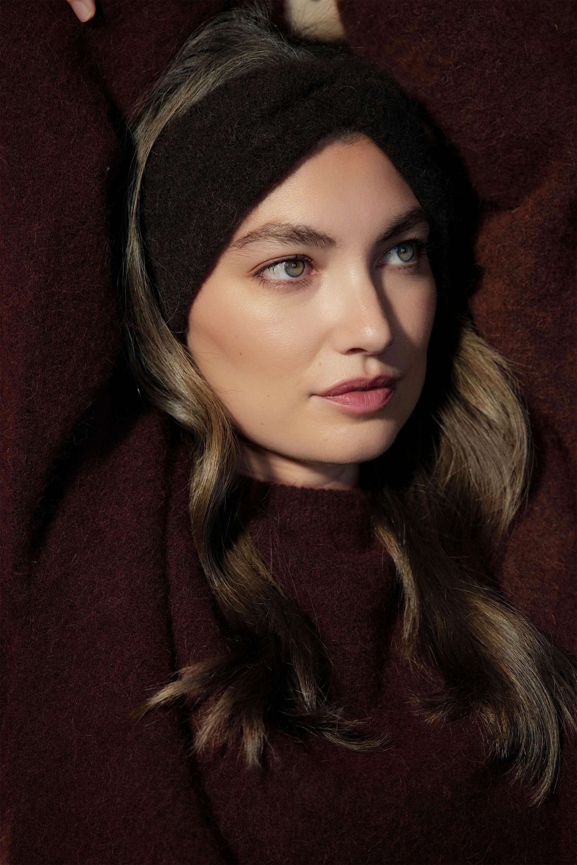 Woman with long brown hair wears Max Mel Luxe Whisper Knit Knot Headband, looking to the side.