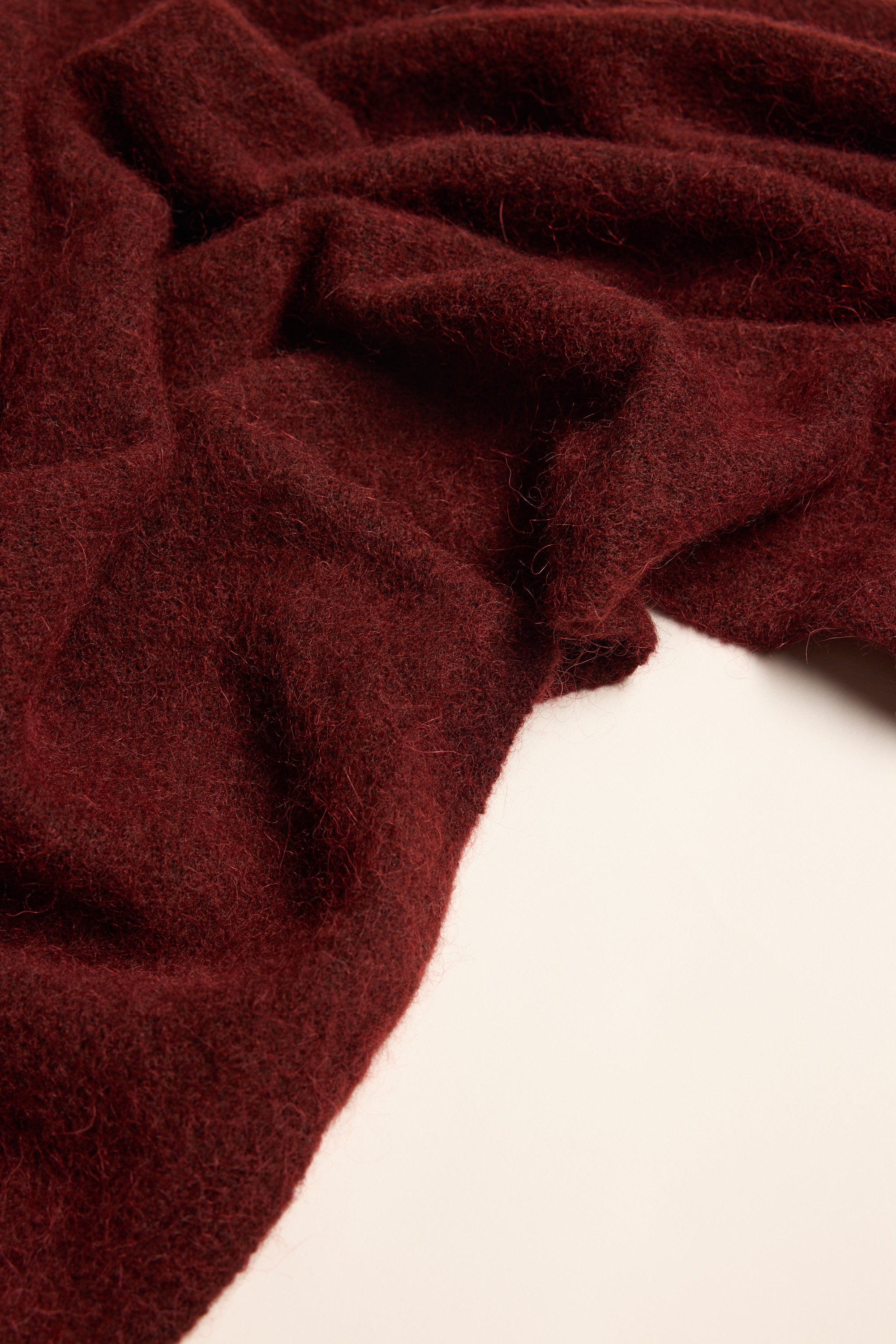 The Max Hailey Luxe Whisper Knit Scarf in textured dark red wool, draped on white.