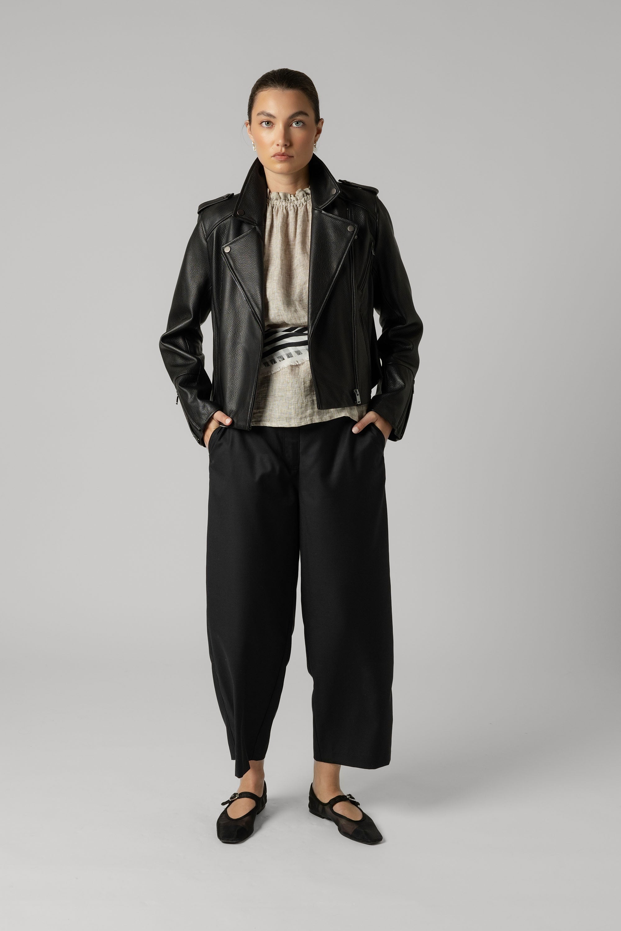 Woman in Max's The Perfect Leather Biker Jacket, loose black pants, and black shoes.