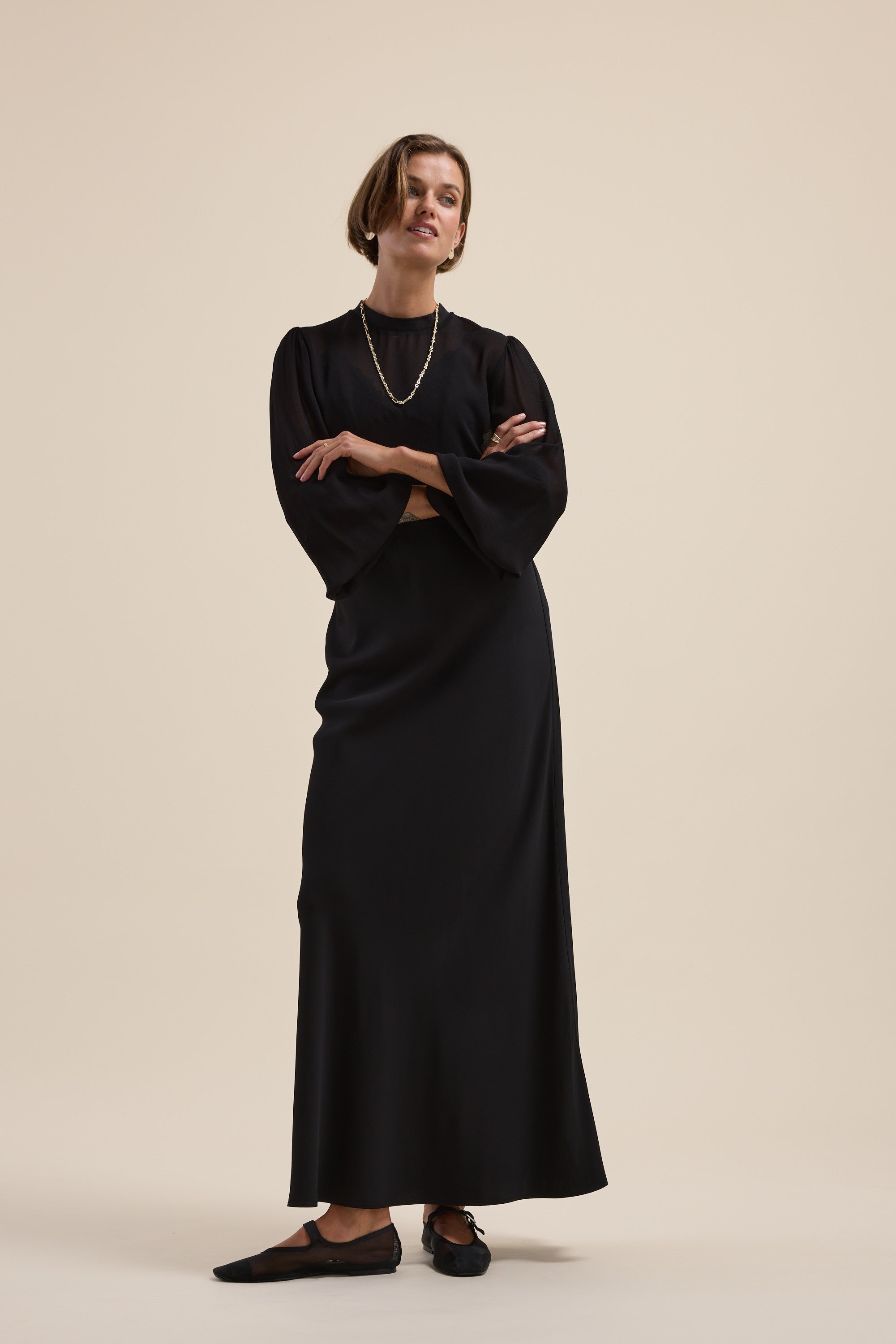 Woman wearing Max's Ultimate Layering Top stands with arms crossed against a plain background.