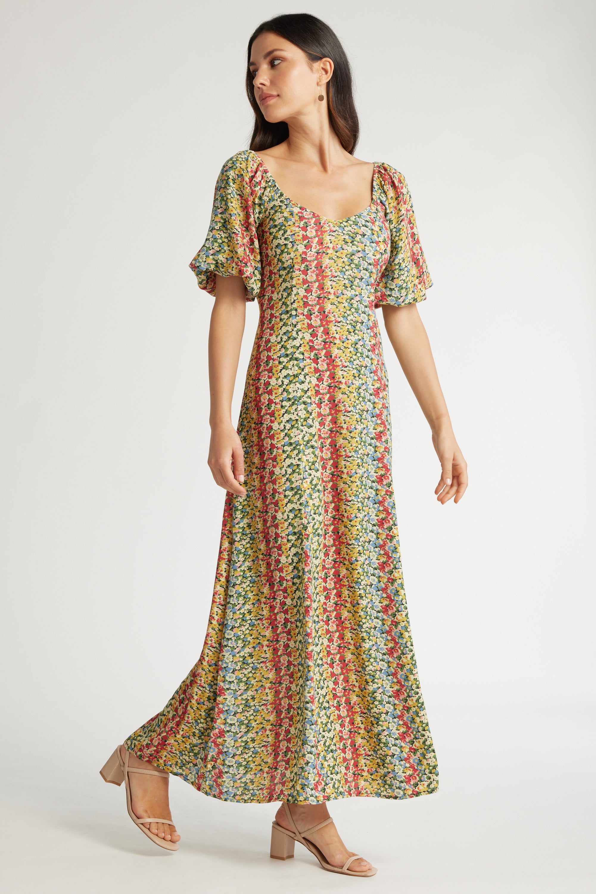A woman wears the Max Elsie Puff Sleeve Midi Dress, featuring a colorful floral print, sweetheart neckline, and short puffed sleeves, paired with tan heeled sandals against a plain light background.