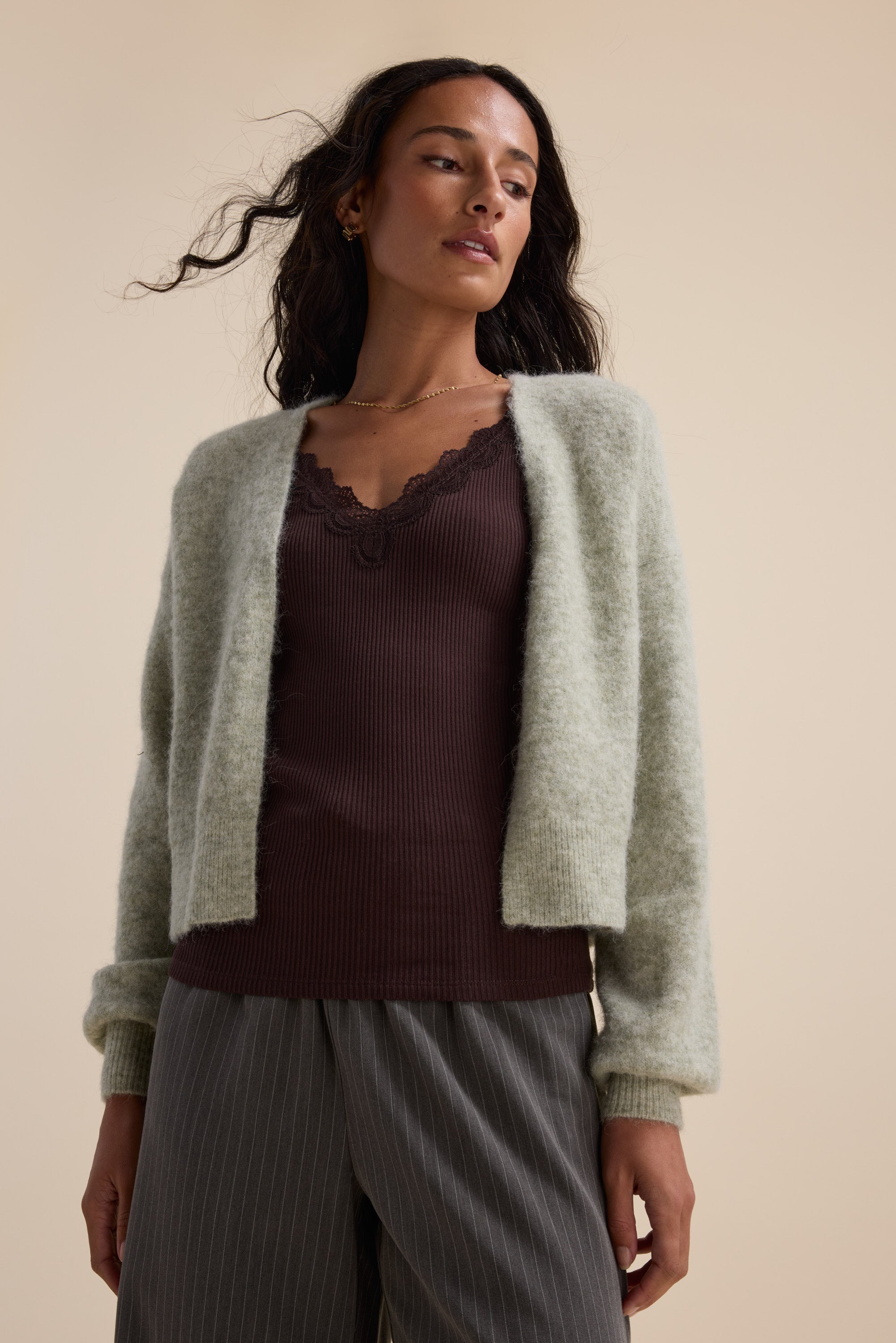 Woman in Max’s The Ultimate Luxe Cardigan, brown lace-trim top, and gray pinstripe pants.