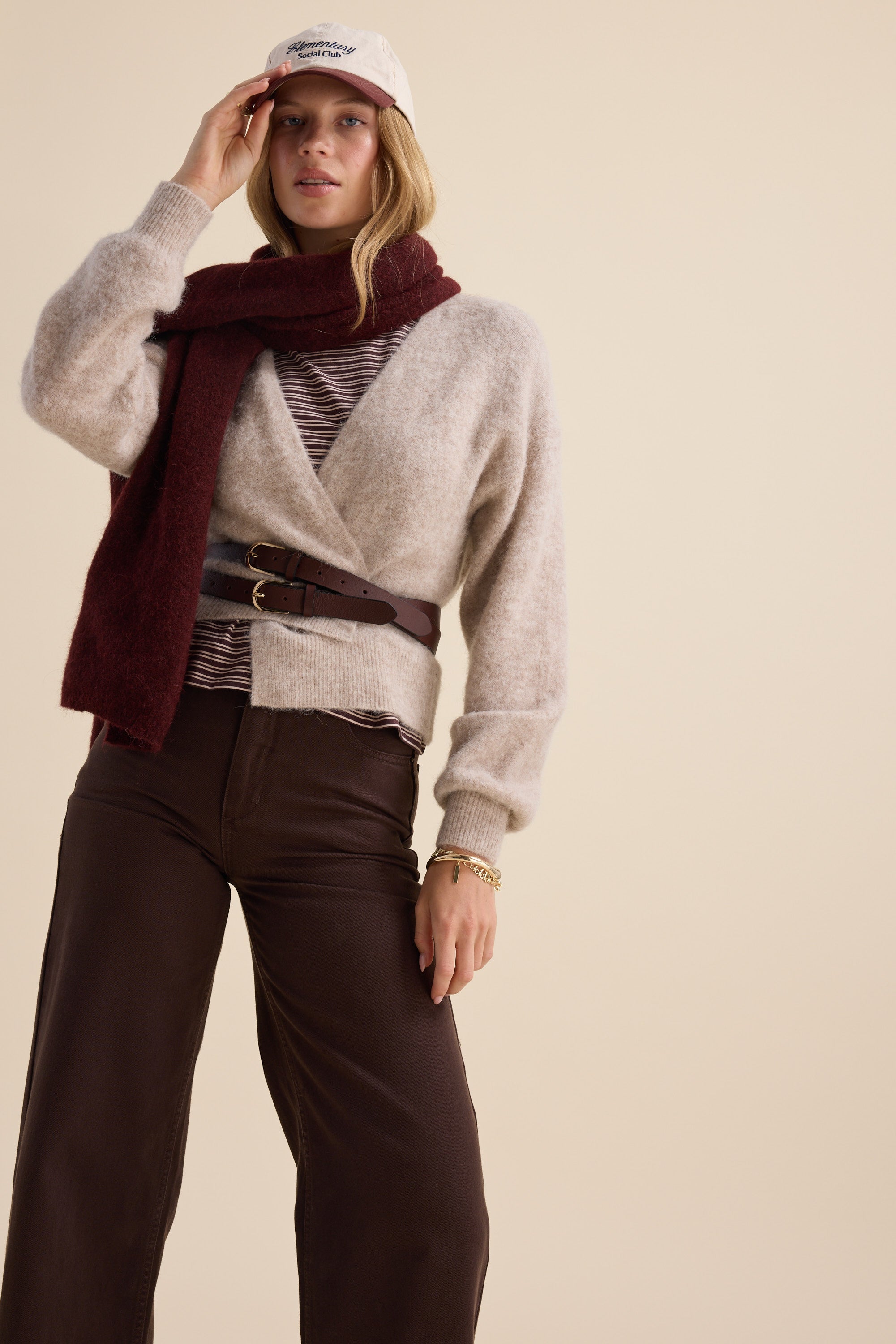 Woman in The Ultimate Luxe Cardigan by Max, cap, scarf, striped top, and brown wide-leg pants.