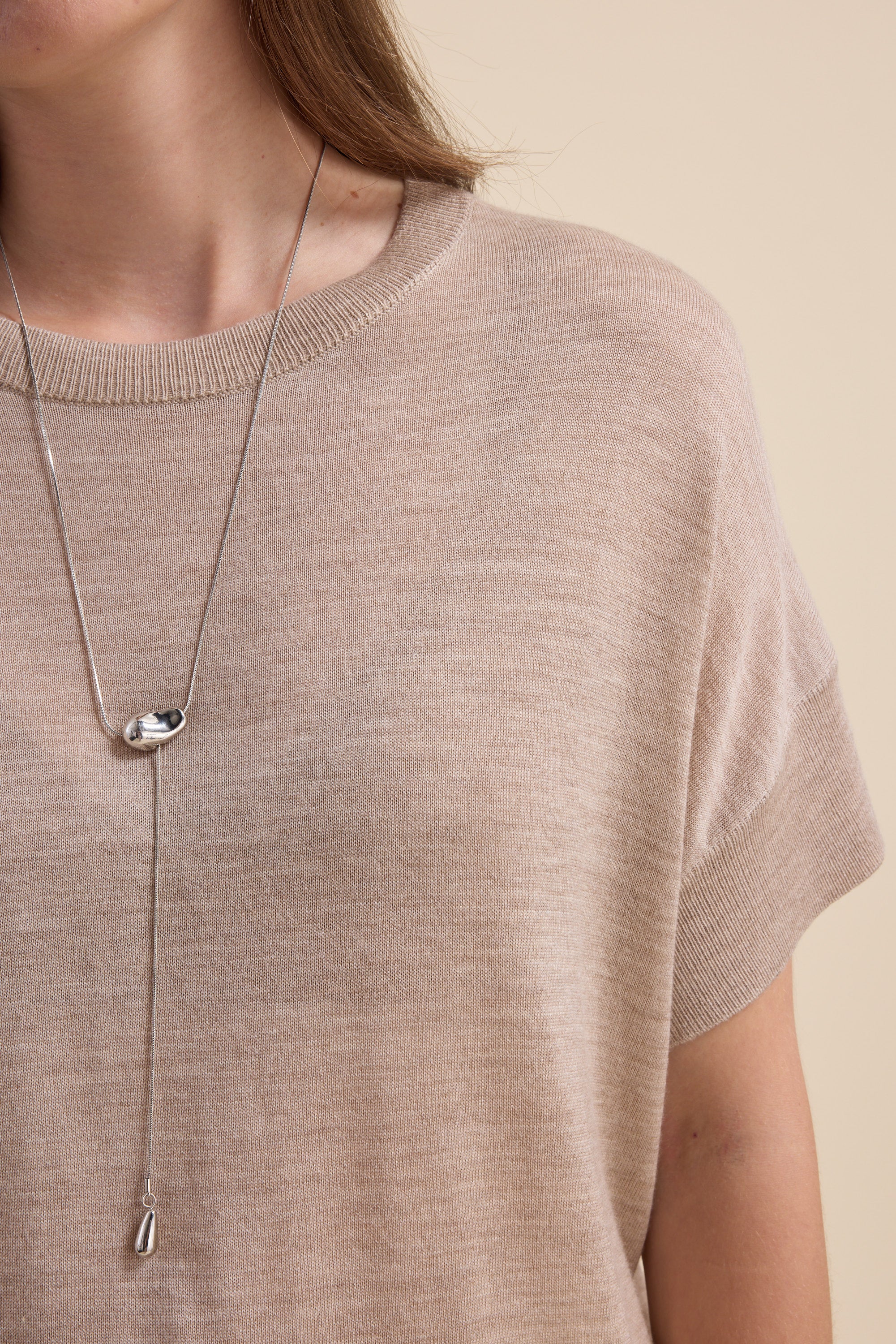 Woman wears The Merino Silk Knit Tee by Max in beige, styled with a silver pendant.