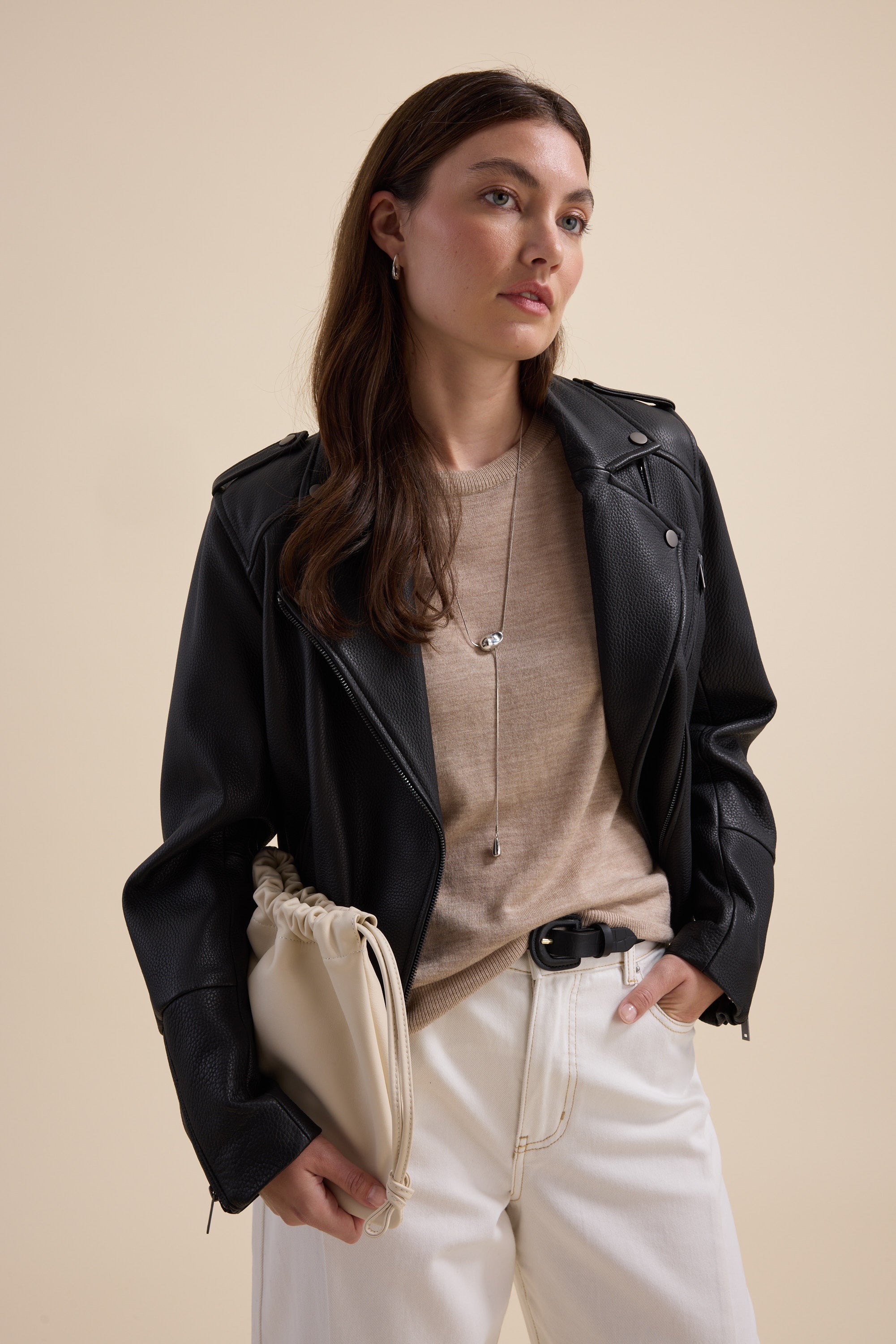Woman in a black leather jacket, Max Merino Silk Knit Tee, white pants, cream clutch.