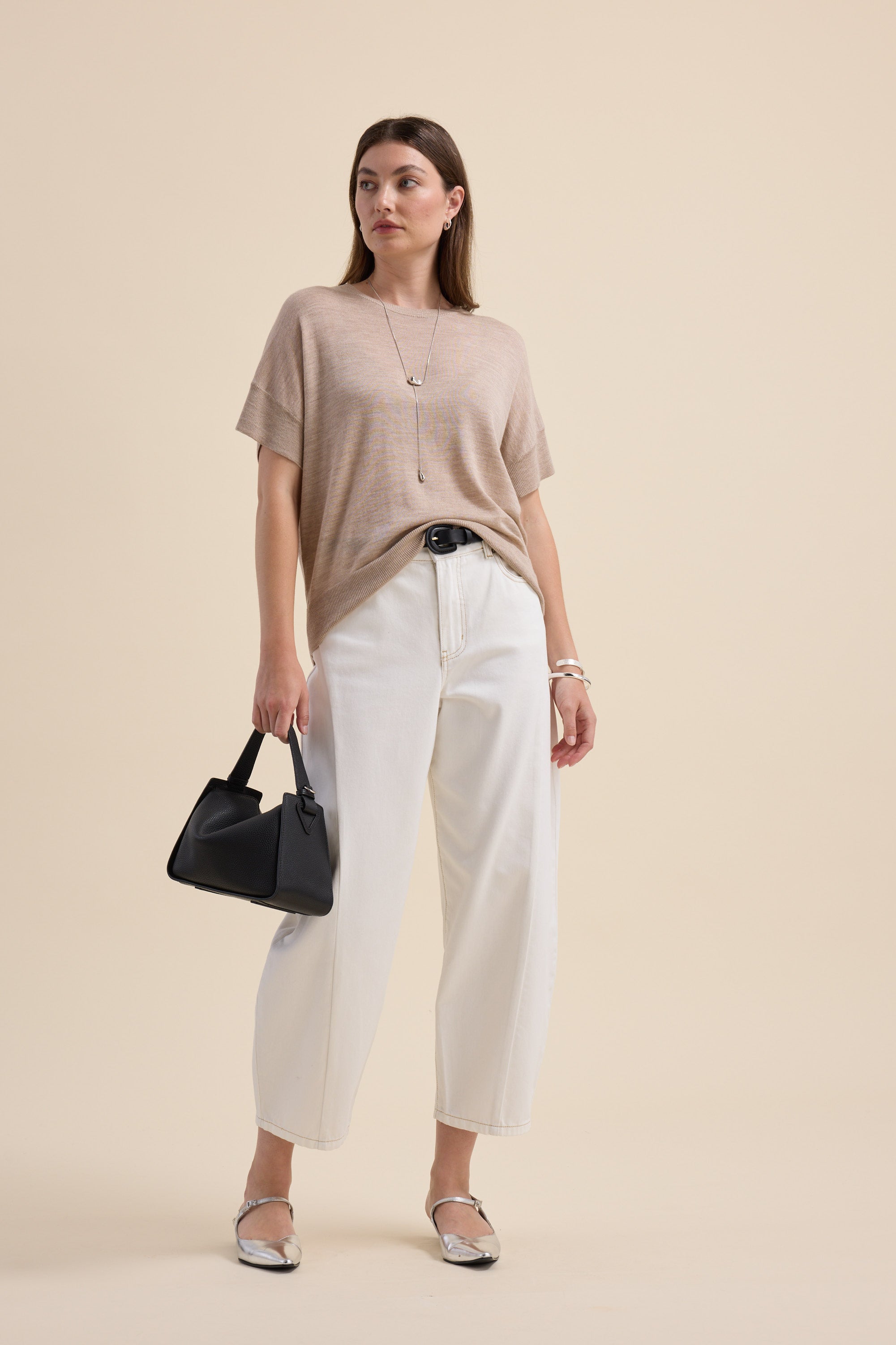 Max’s Merino Silk Knit Tee styled with white pants, silver shoes, and a black handbag.