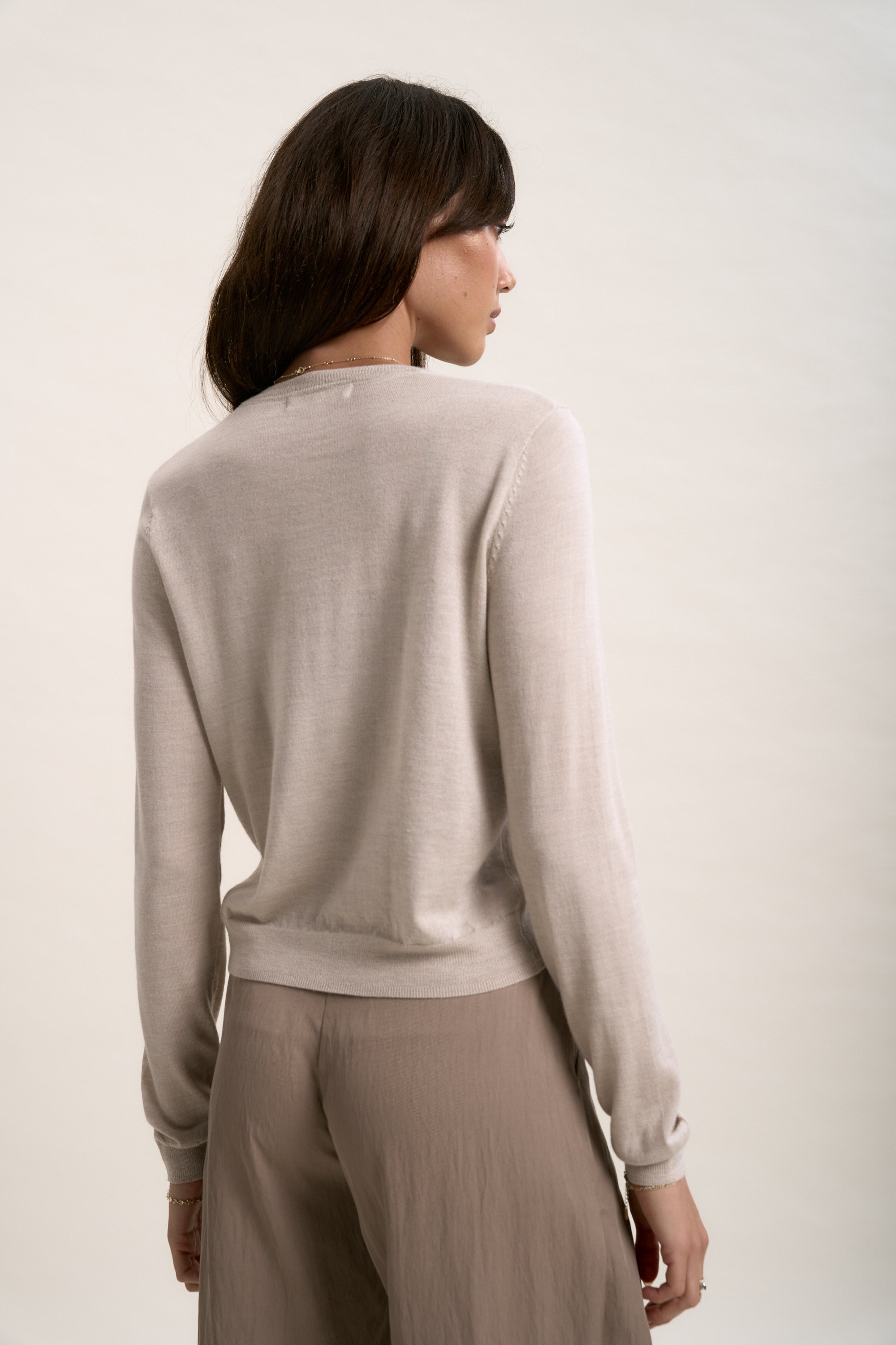 A woman wears The Merino Silk Cardigan by Max in white.