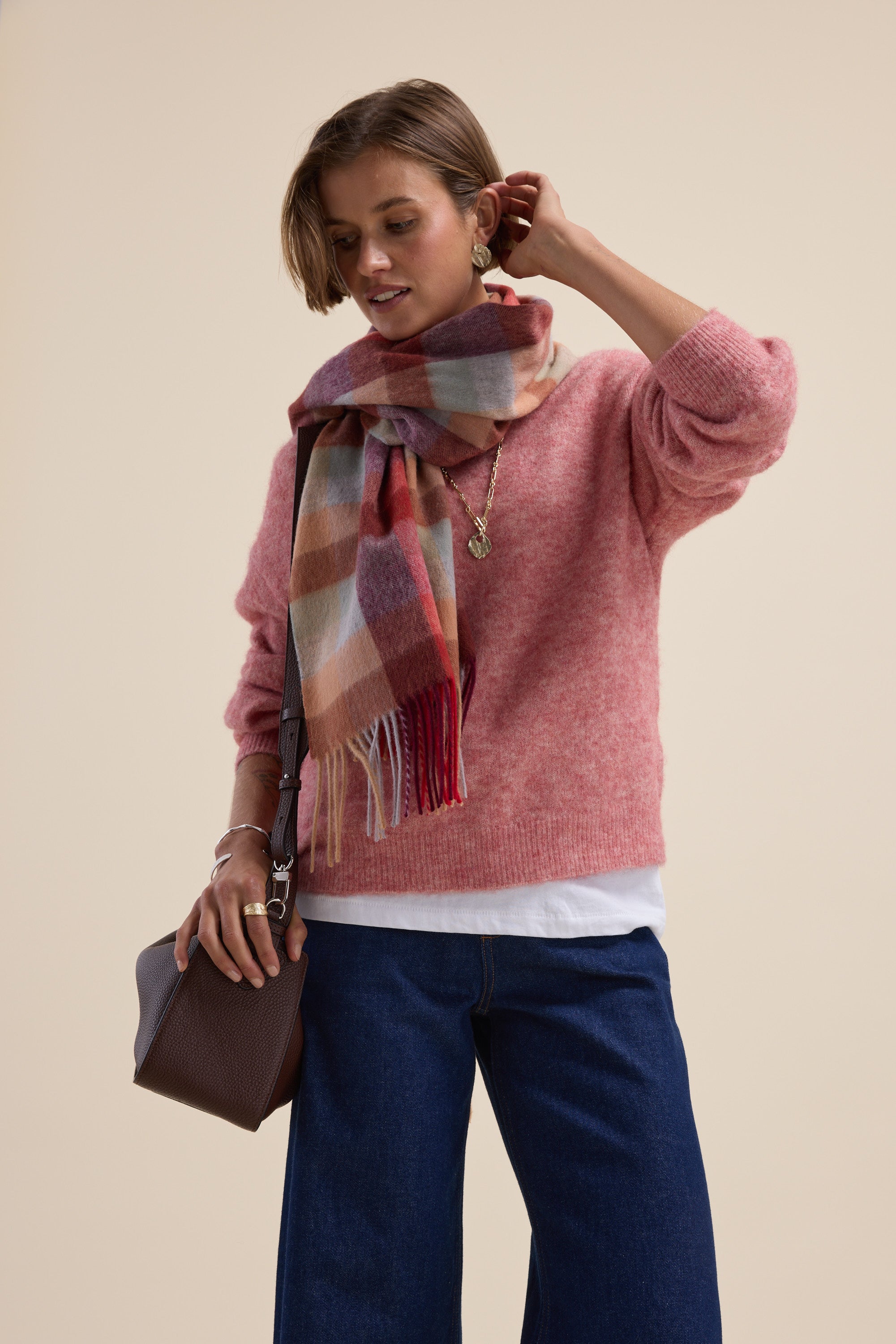Woman in Max Hayley Luxe Whisper Crew Neck Sweater, plaid scarf, jeans, and brown bag.