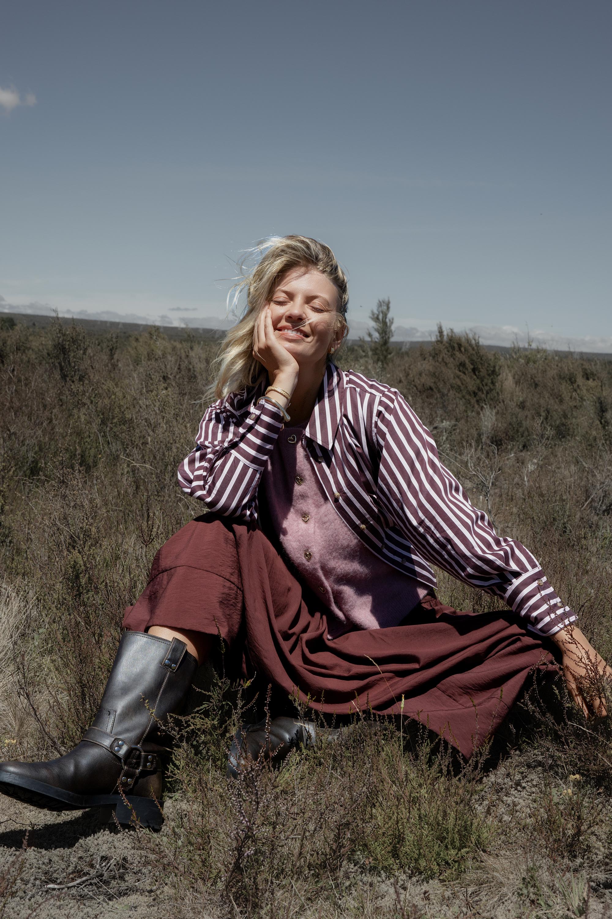 Woman in Leah Stripe Detail Shirt by Max sits outdoors, smiling with eyes closed.