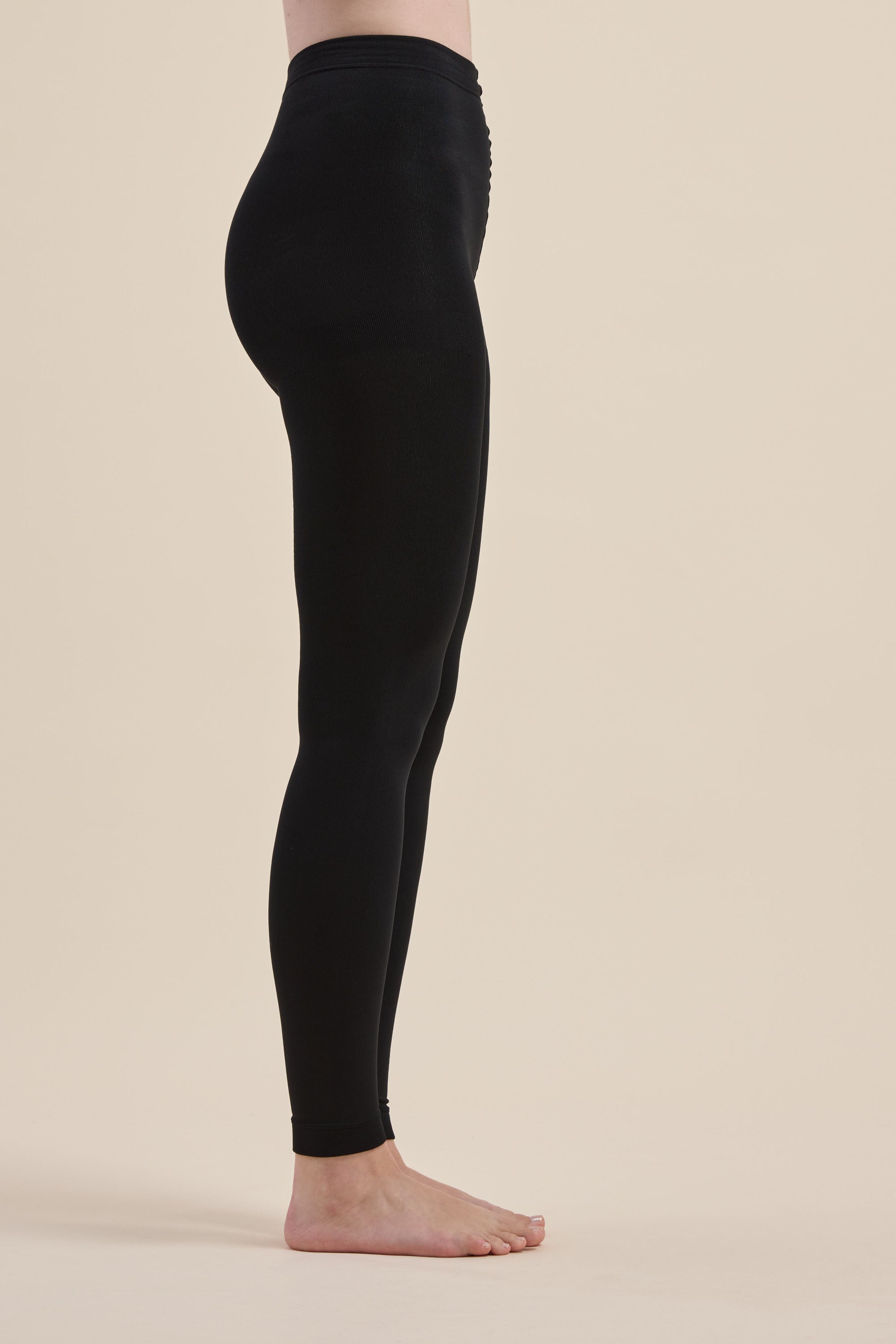 Person stands barefoot in profile wearing Max Recycled Fleecy Legging against plain background.