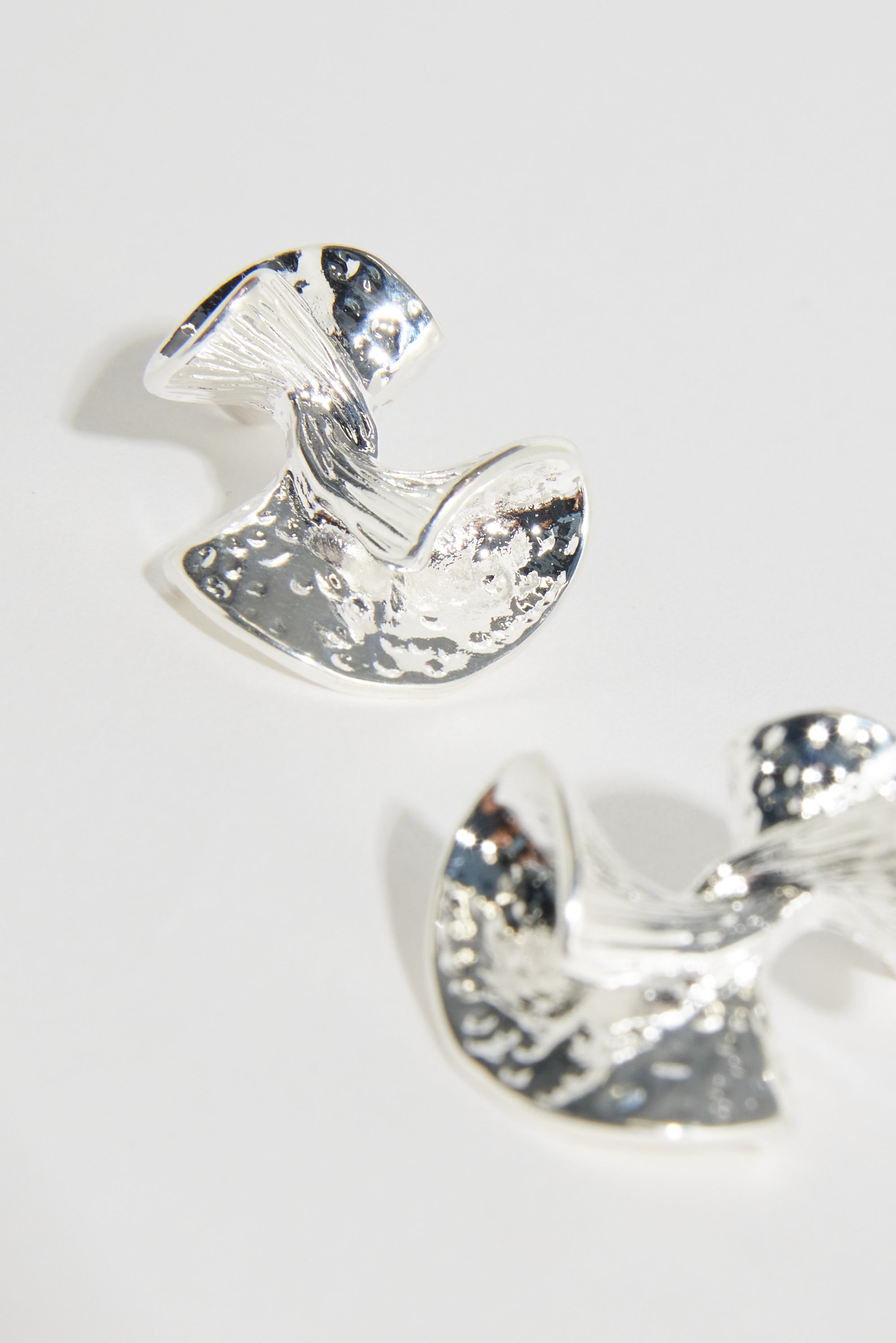 The Bela Sonder Monroe Earrings by Bela Sonder feature a twisted, organic design with a textured, hammered sterling silver surface that beautifully reflects light against a light background.