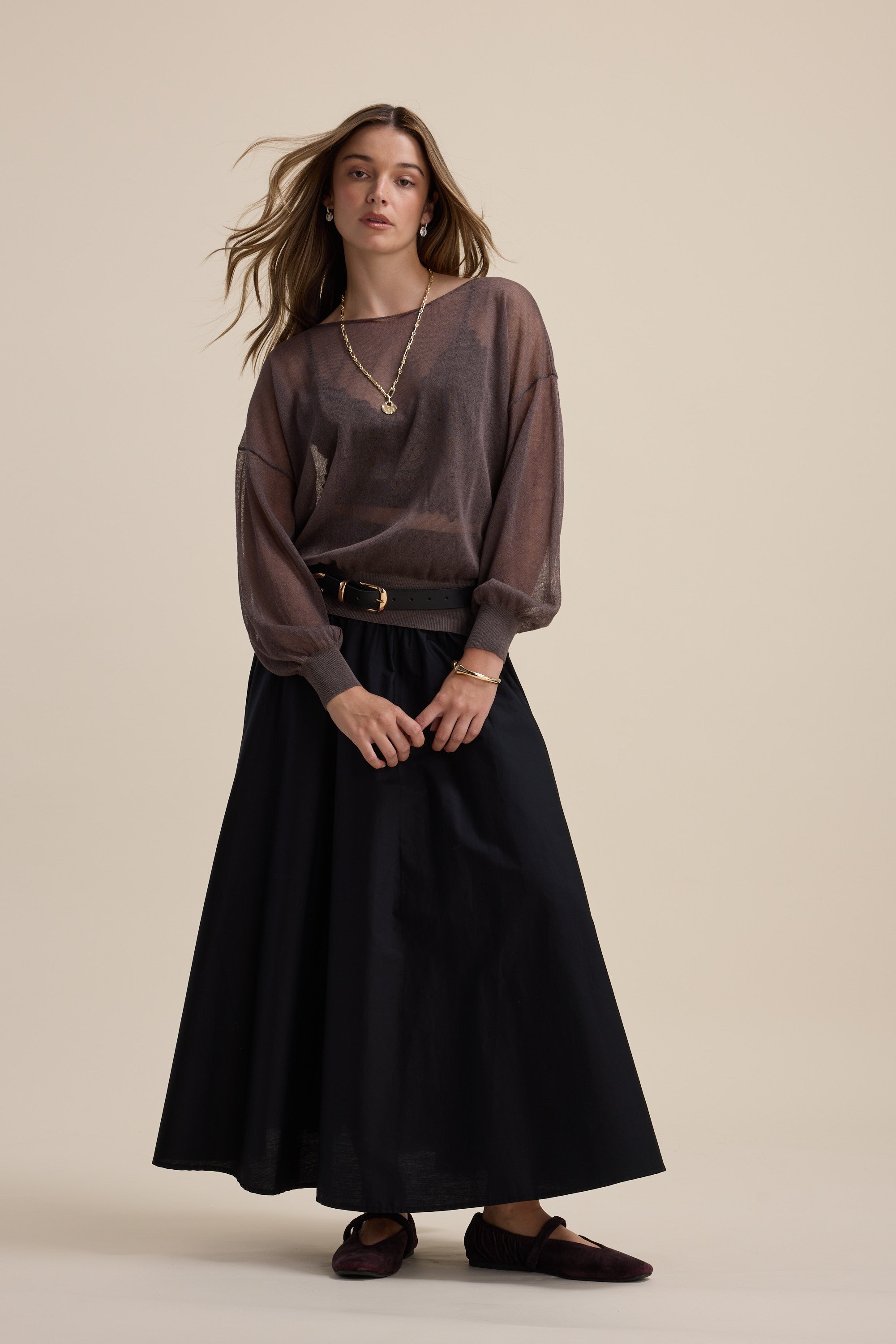 Model wears the Addie Sheer Knitted Top by Max with a long black skirt against a beige background.