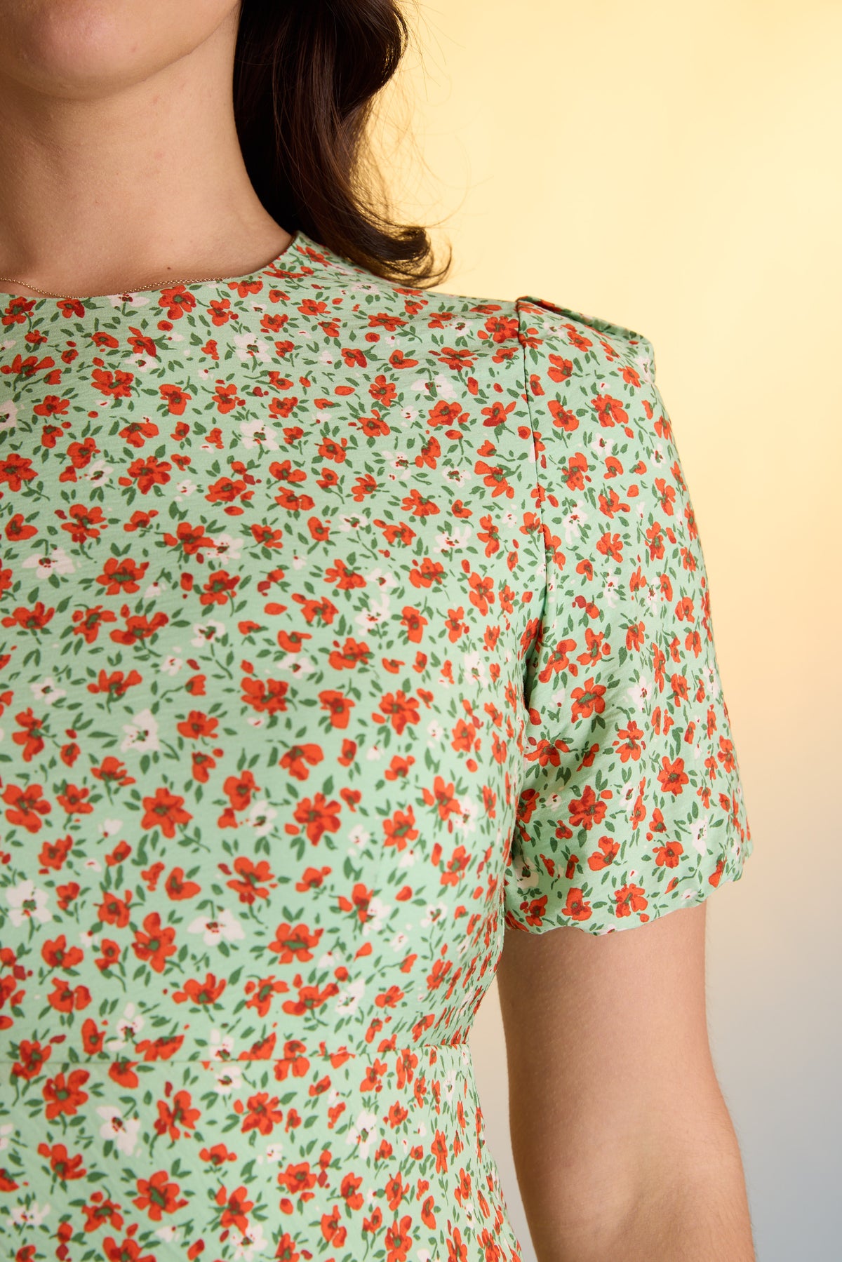 Woman in Max Poppy Short Sleeved Dress, green floral print, puff sleeves, shoulder to waist.