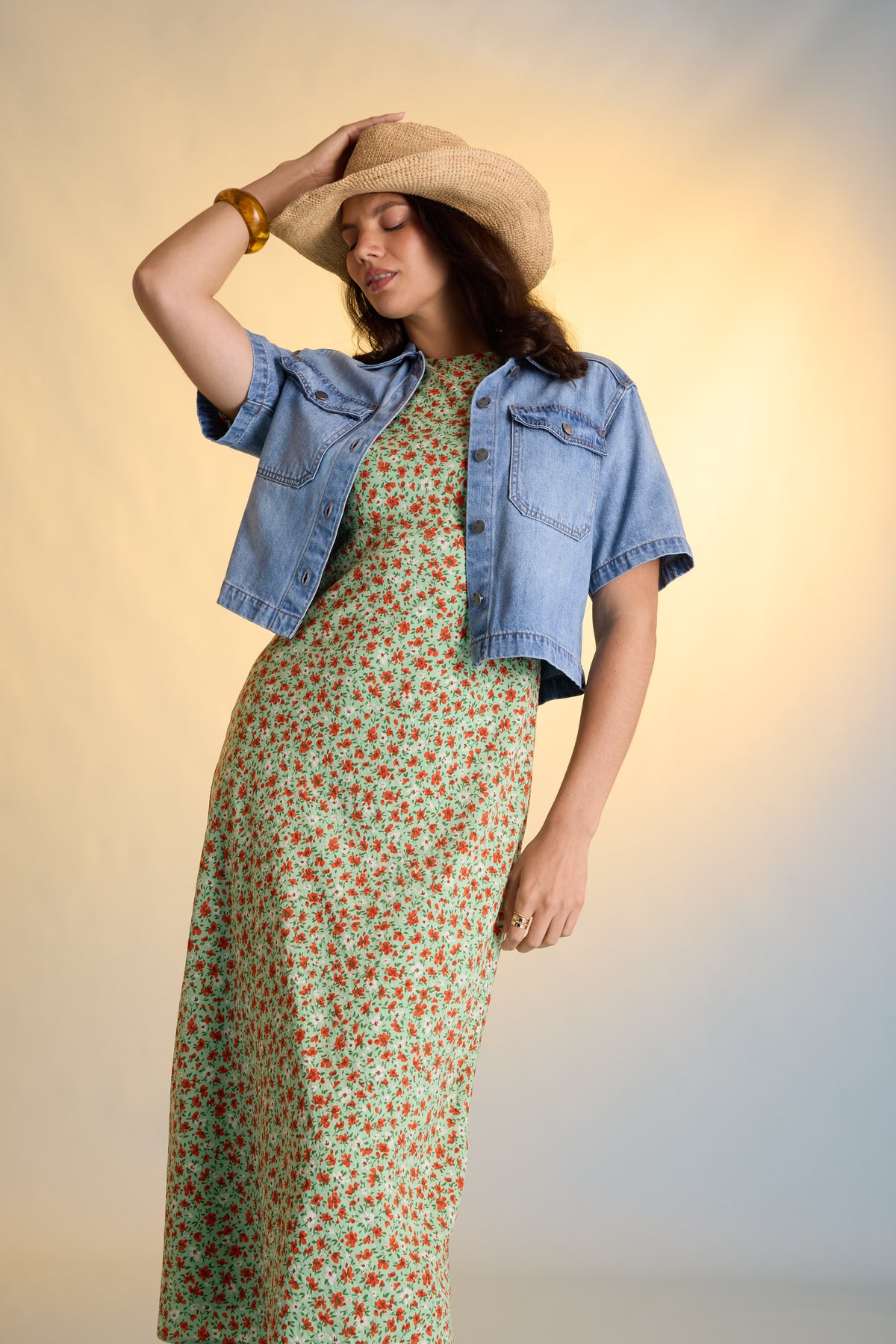 Woman in Max Poppy Short Sleeved Dress, denim jacket, and straw hat poses gracefully.