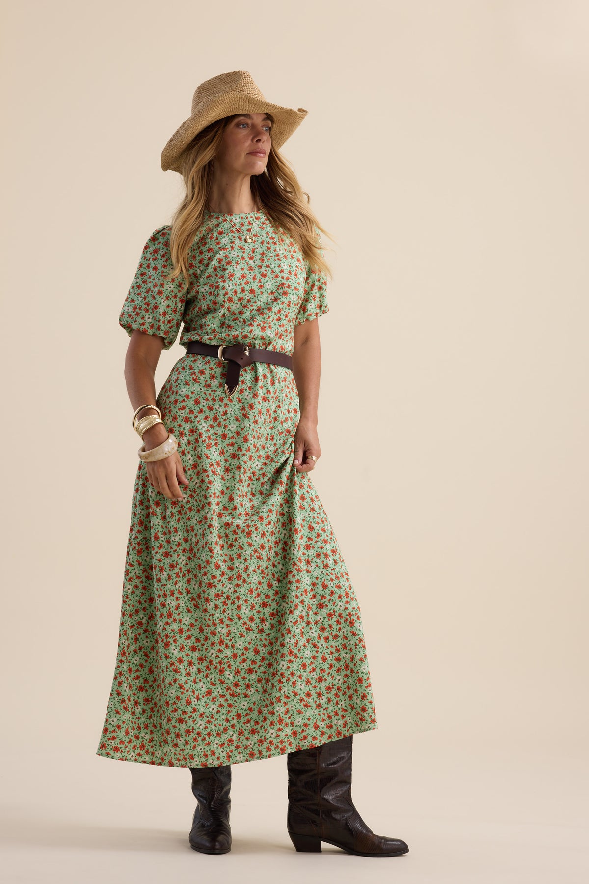 Woman in Max’s Poppy Short Sleeved Dress, cowboy boots, hat, and bangles poses simply.