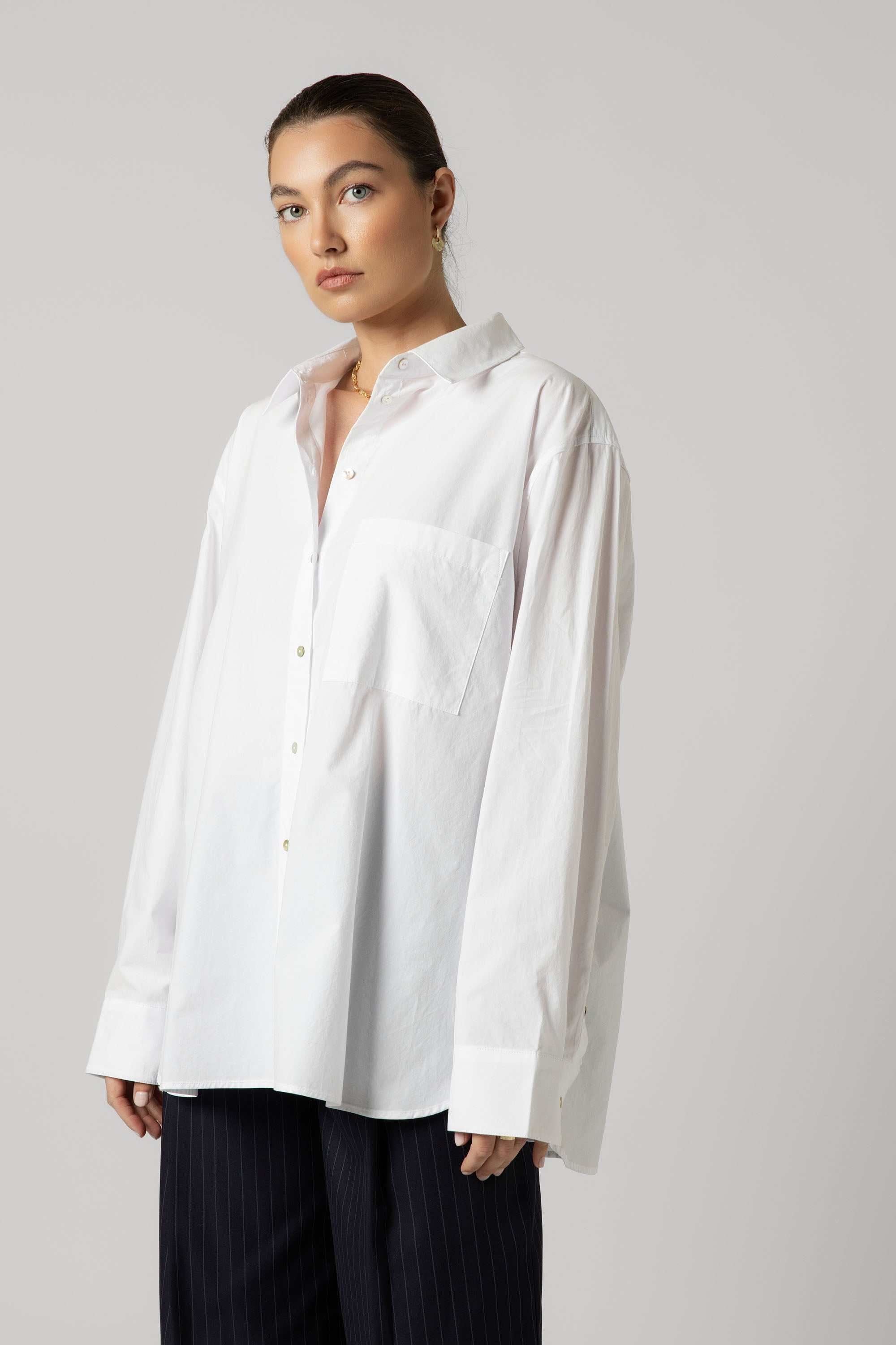 Woman wears the Max Everyday Tailored Shirt with dark pants against a plain background.