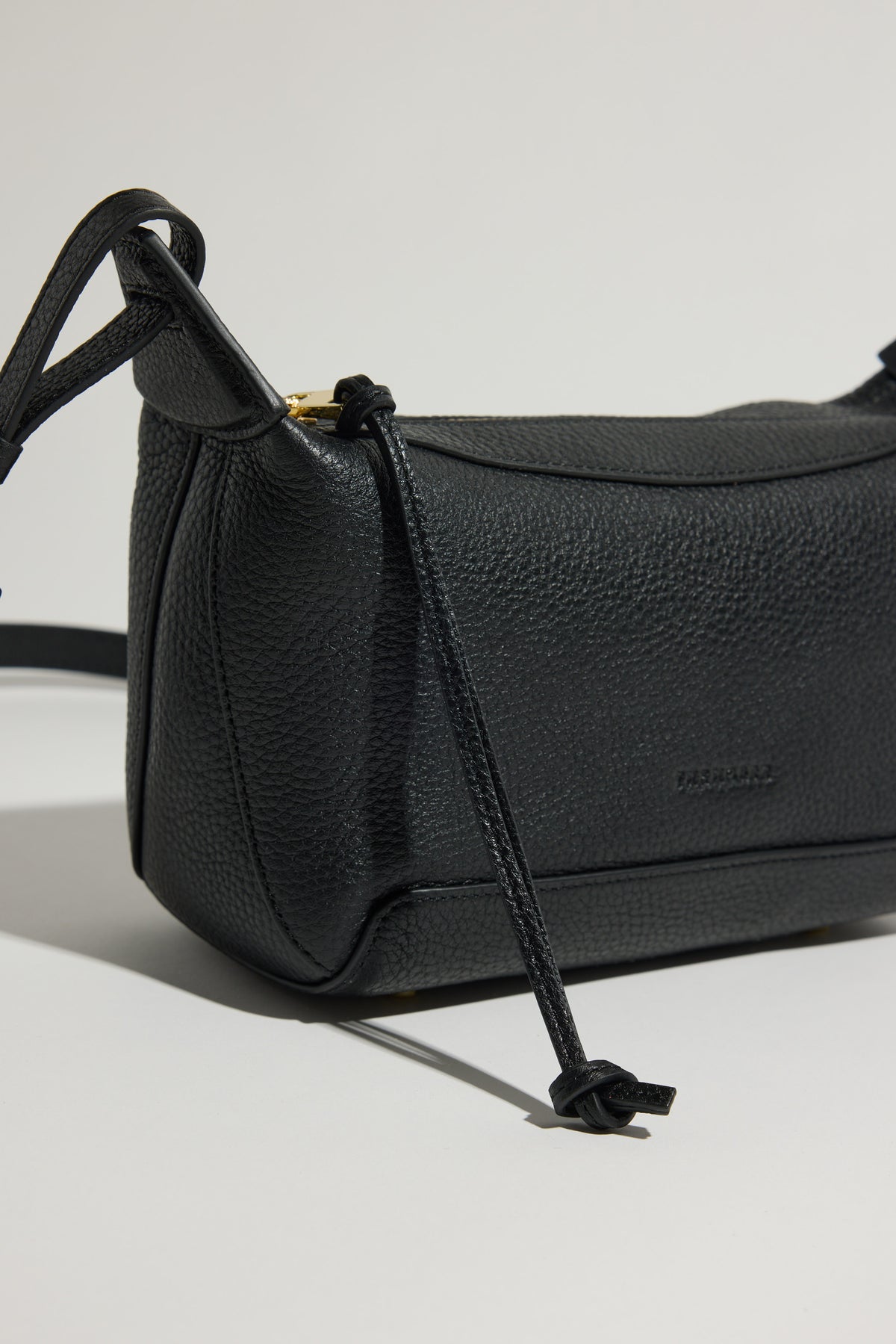 The Horse Mini Lou Bag in black pebble leather with knotted straps on a light background.