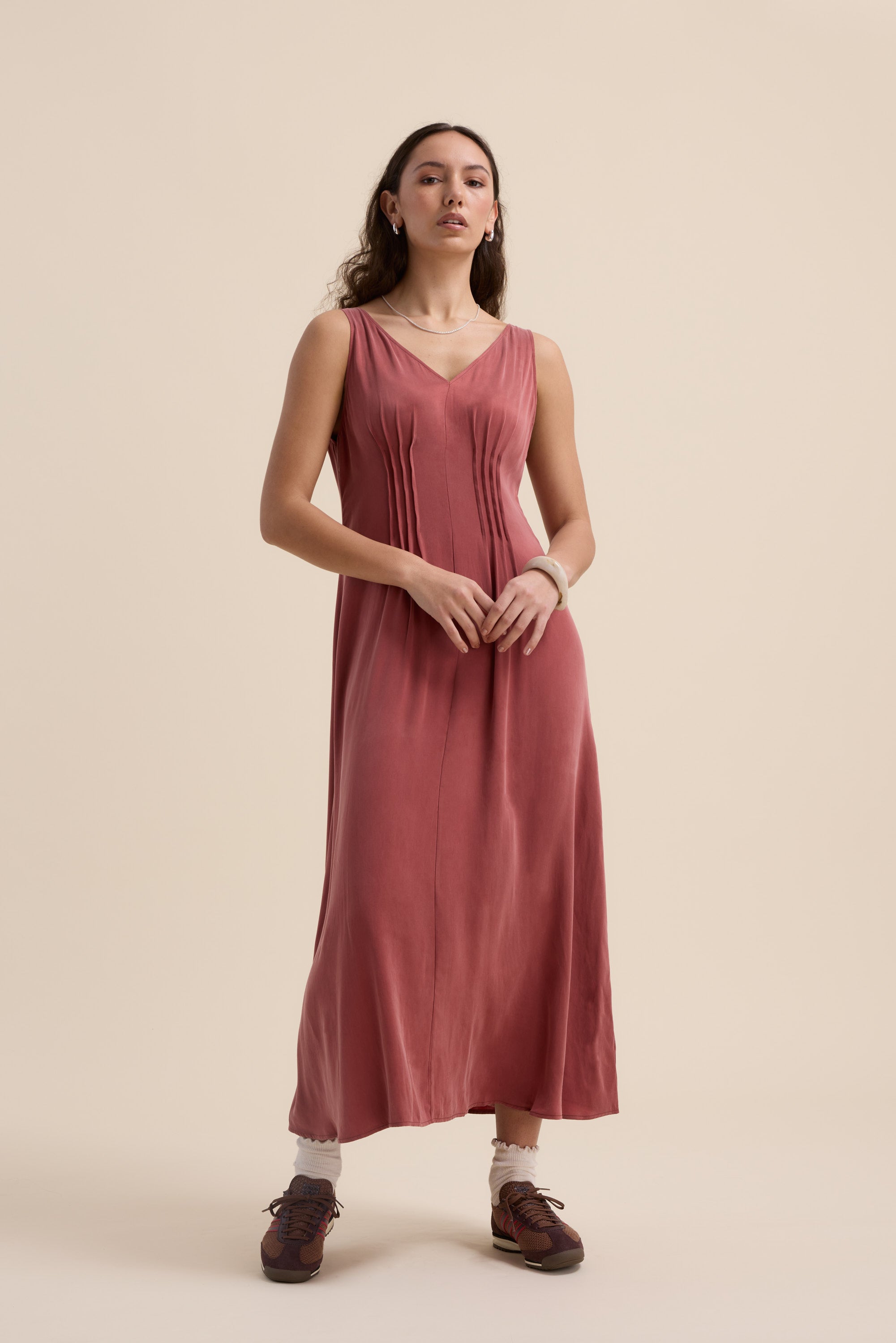 Woman in Max's Cara Pleat Detail Dress, sleeveless rose maxi, posing in brown shoes and white socks.