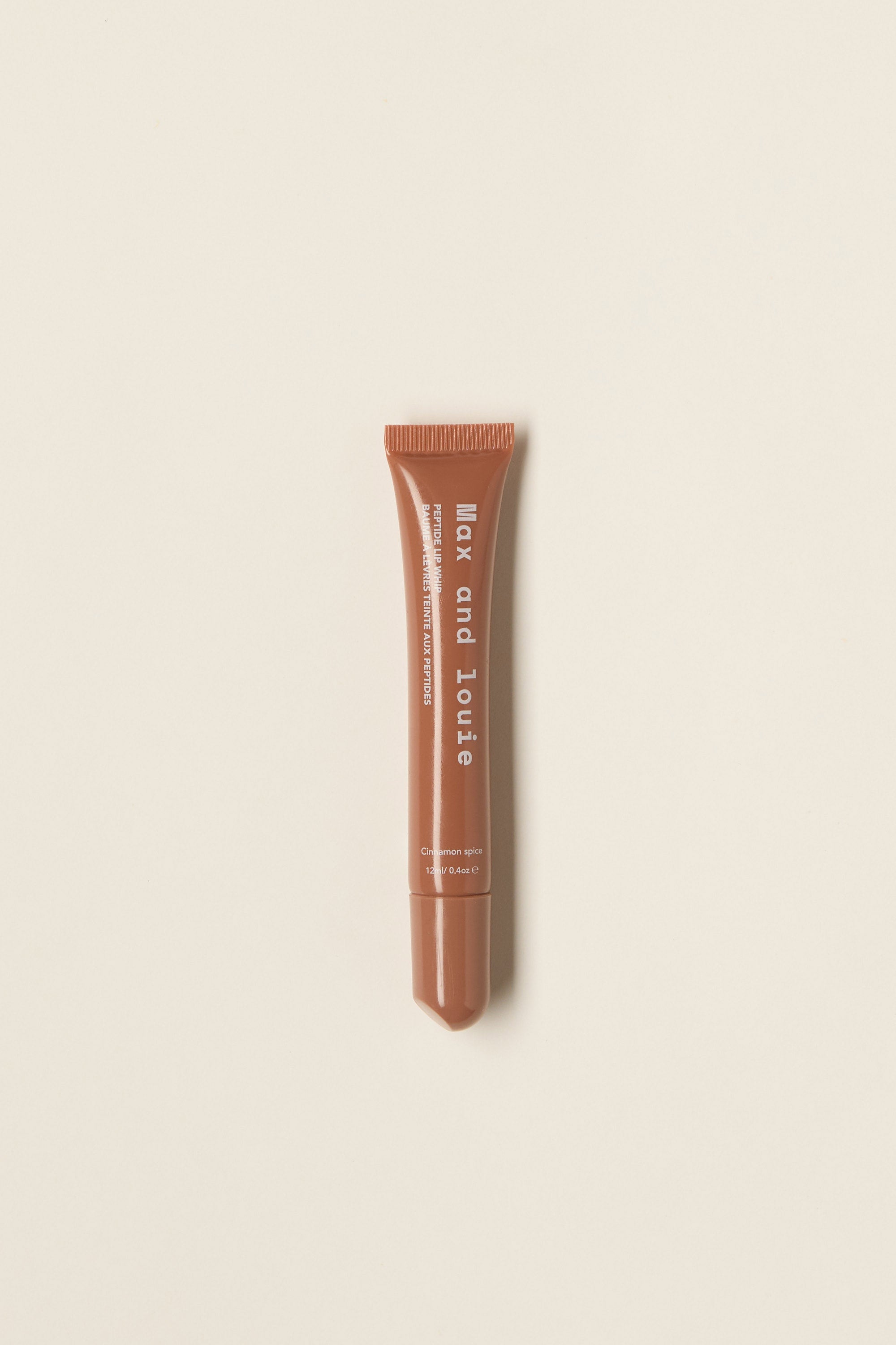 A brown Max and Louie Peptide Lip Whip tube with white text stands vertically on a plain, light beige background.
