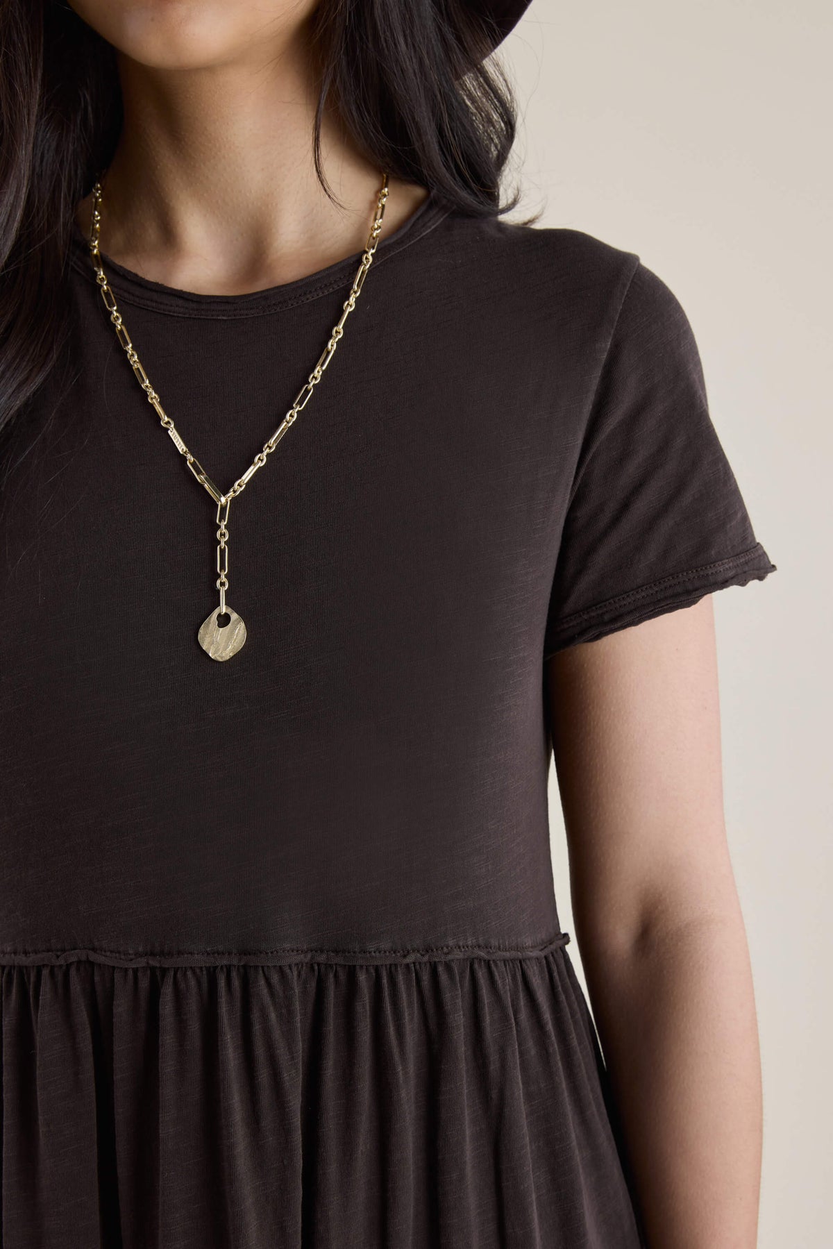 Woman in the Elementary Jersey Tiered Dress and a gold chain necklace with round pendant.