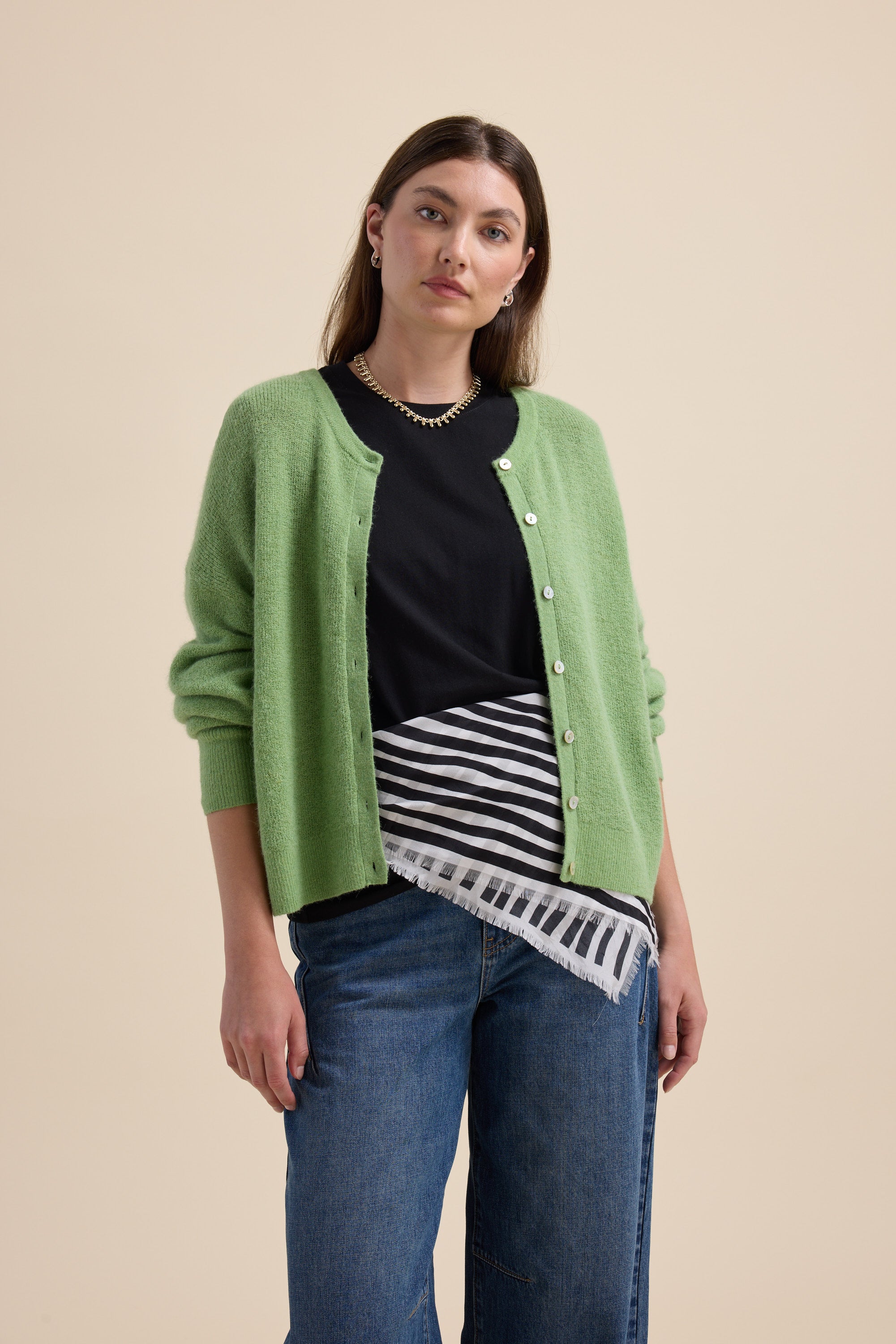 Woman in green cardigan and jeans, wearing Max’s The Good Earth Cotton Crew Tee.