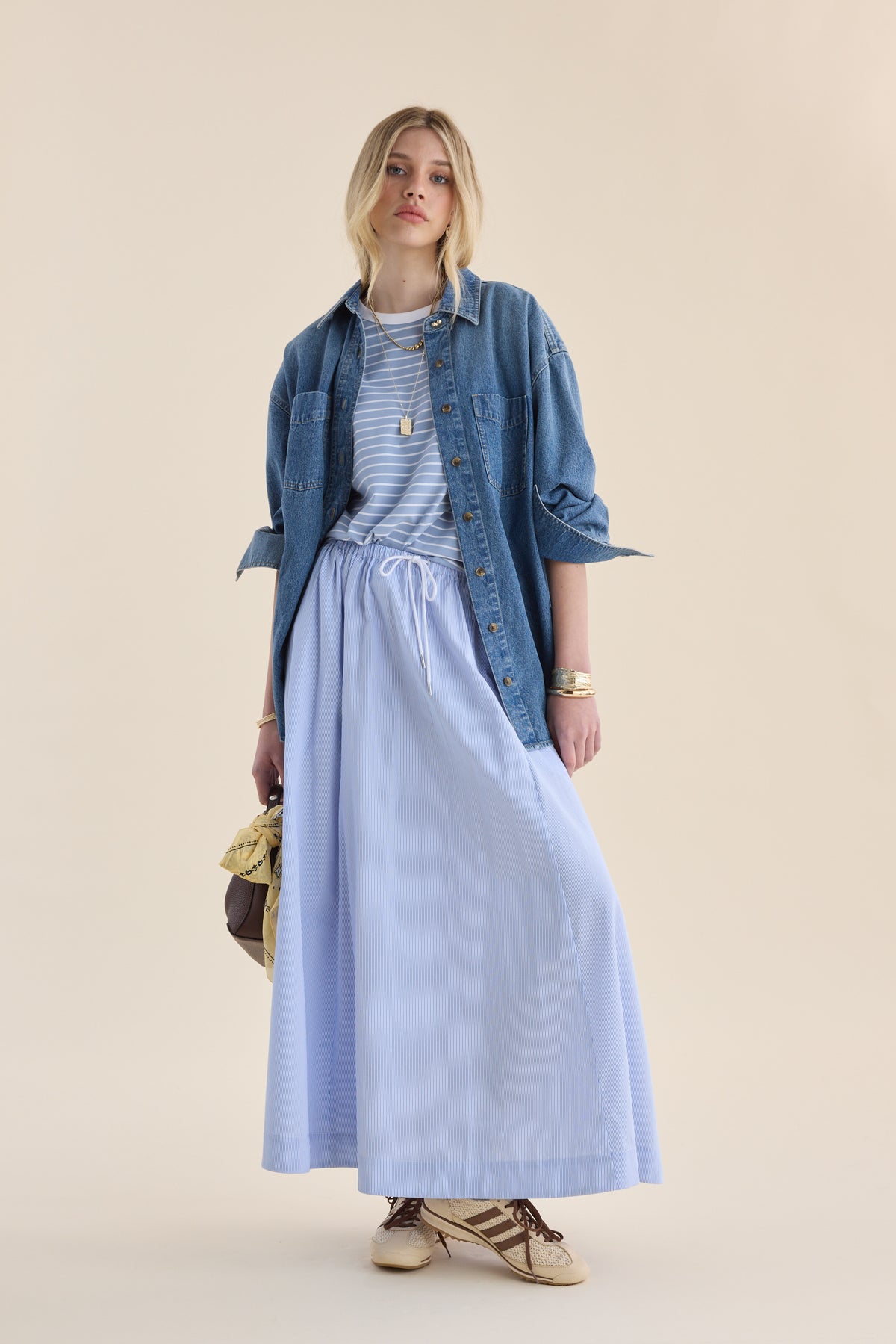 Woman in Max’s Perfect SS Crew Neck Tee, long light blue skirt, holding a brown handbag.