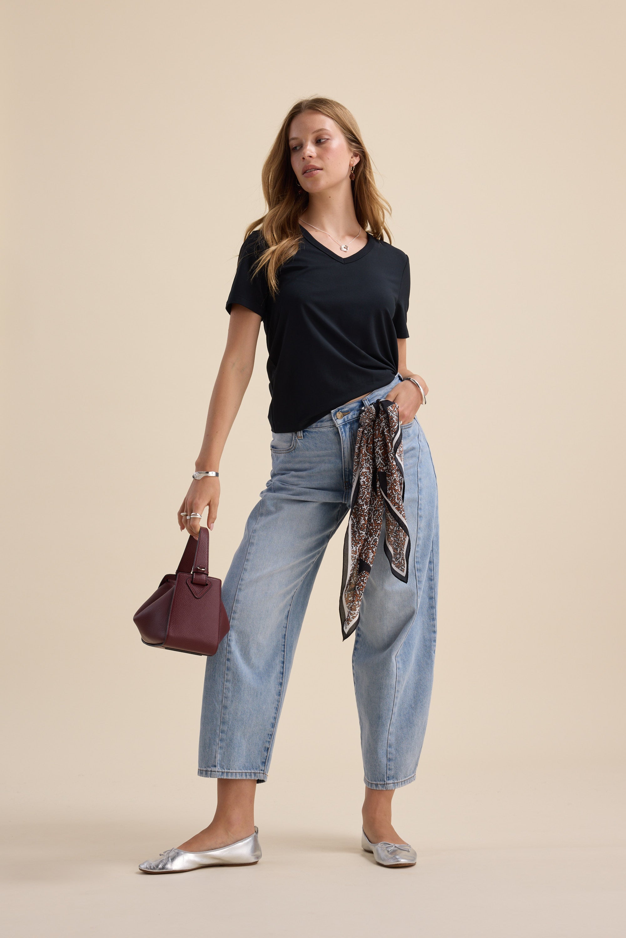 Woman in Max’s Perfect Short Sleeve V Neck Tee, light blue jeans, silver flats, maroon bag, scarf.