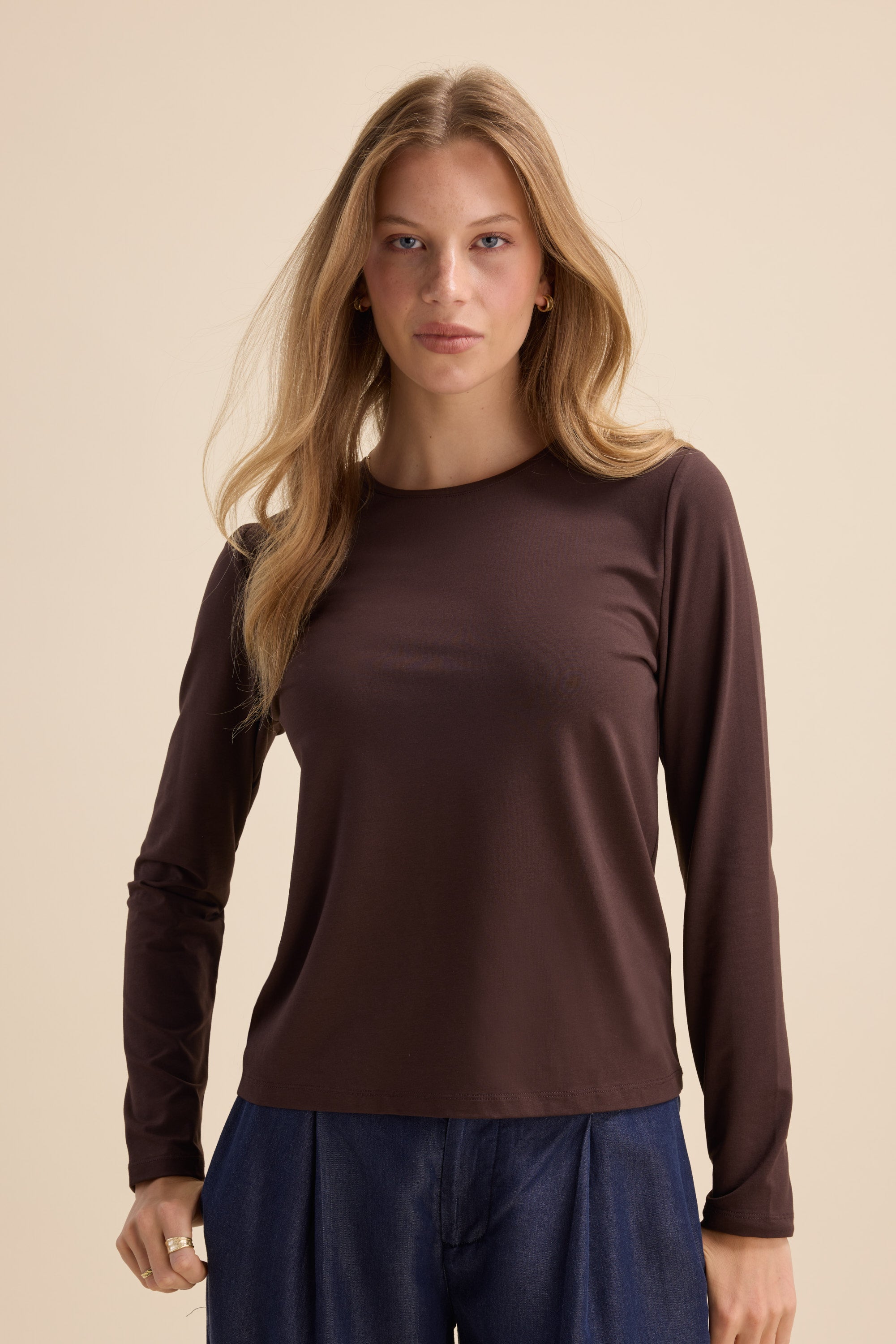 Woman in Max's The Perfect Long Sleeve Crew Tee and blue pants against a beige background.