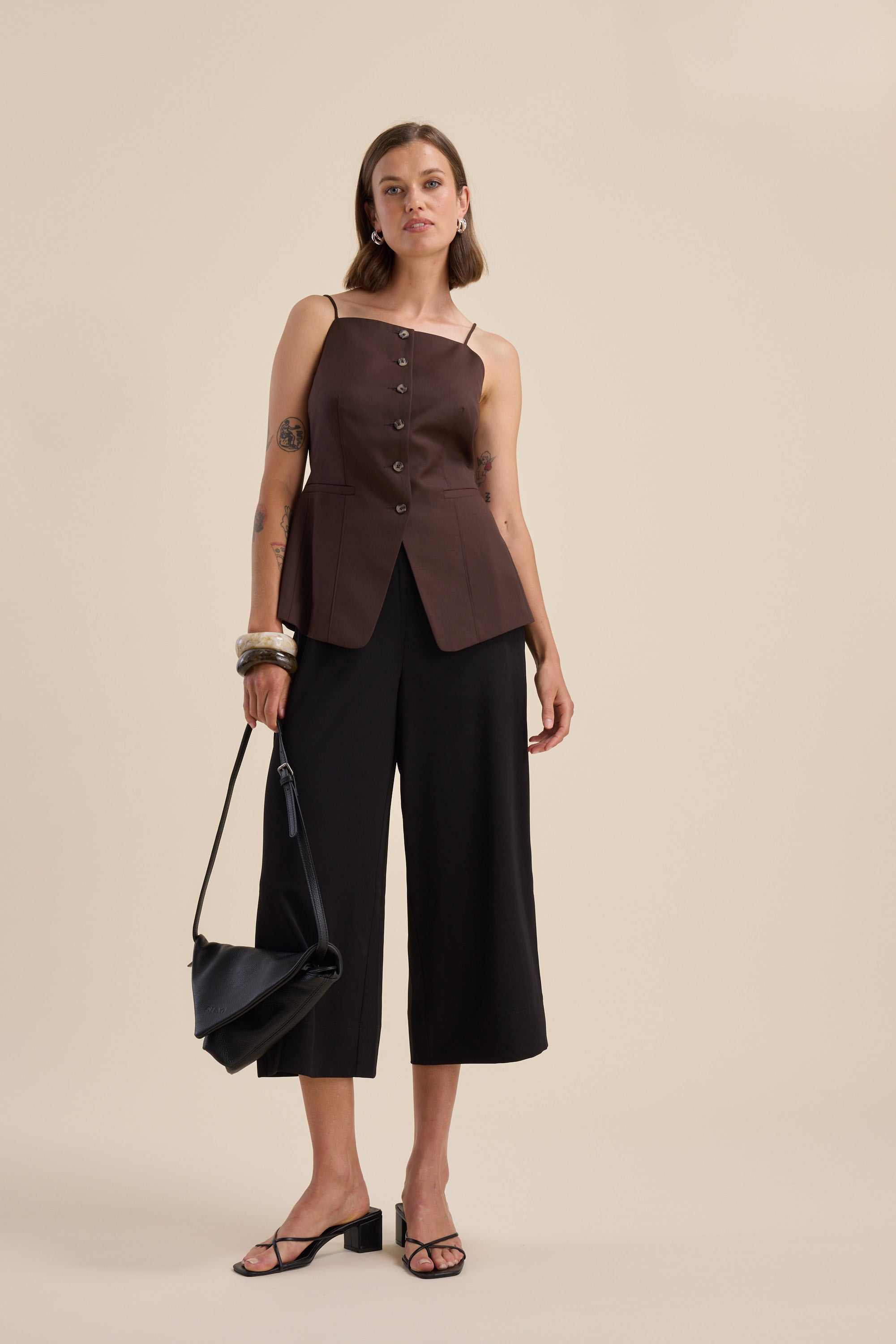 Woman in The Easy Care Wide Leg Crop Pants by Max, a brown top, sandals, and a black handbag.