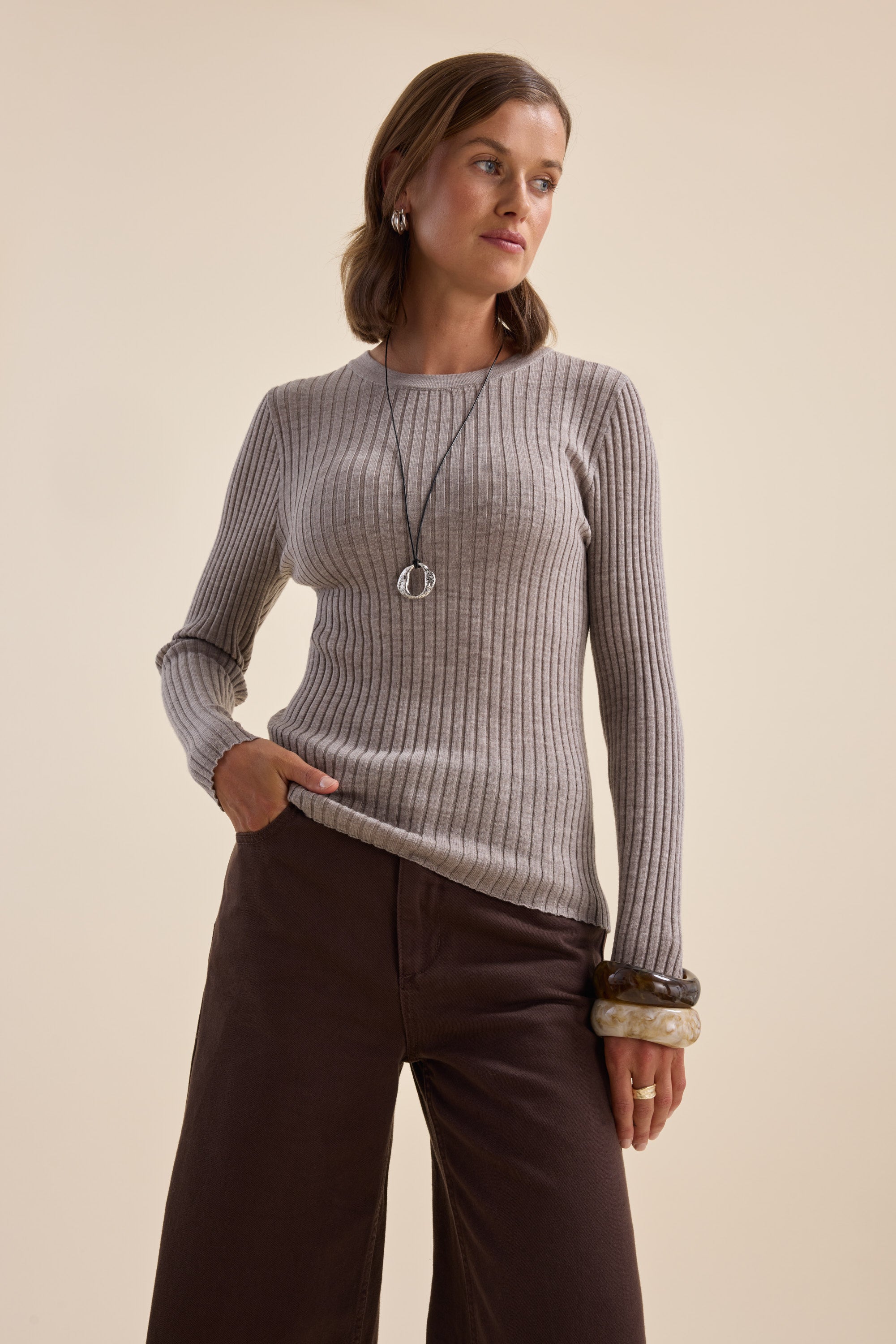 Woman in Elementary ZQ Merino Crew Neck Top, gray, with brown pants and jewelry.