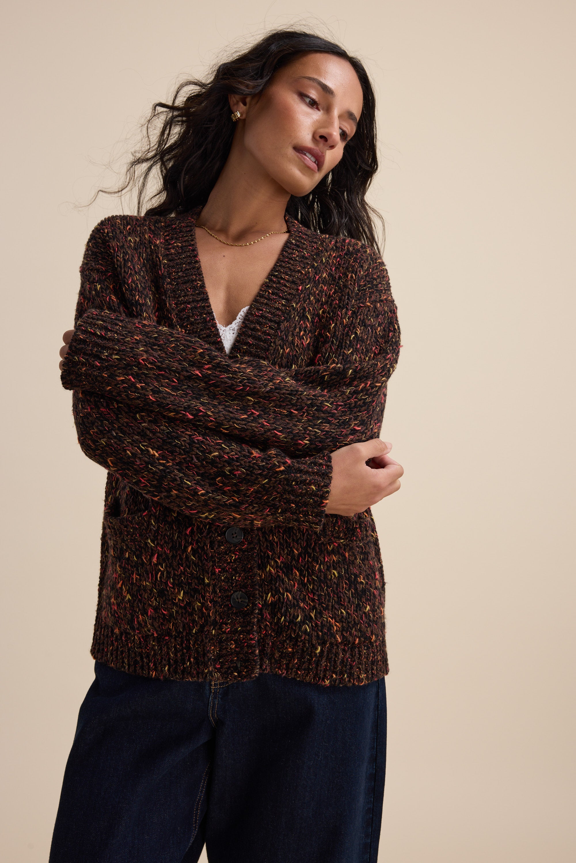 Woman in Elementary Oversized Merino Blend Cardigan and dark jeans poses with arms crossed.
