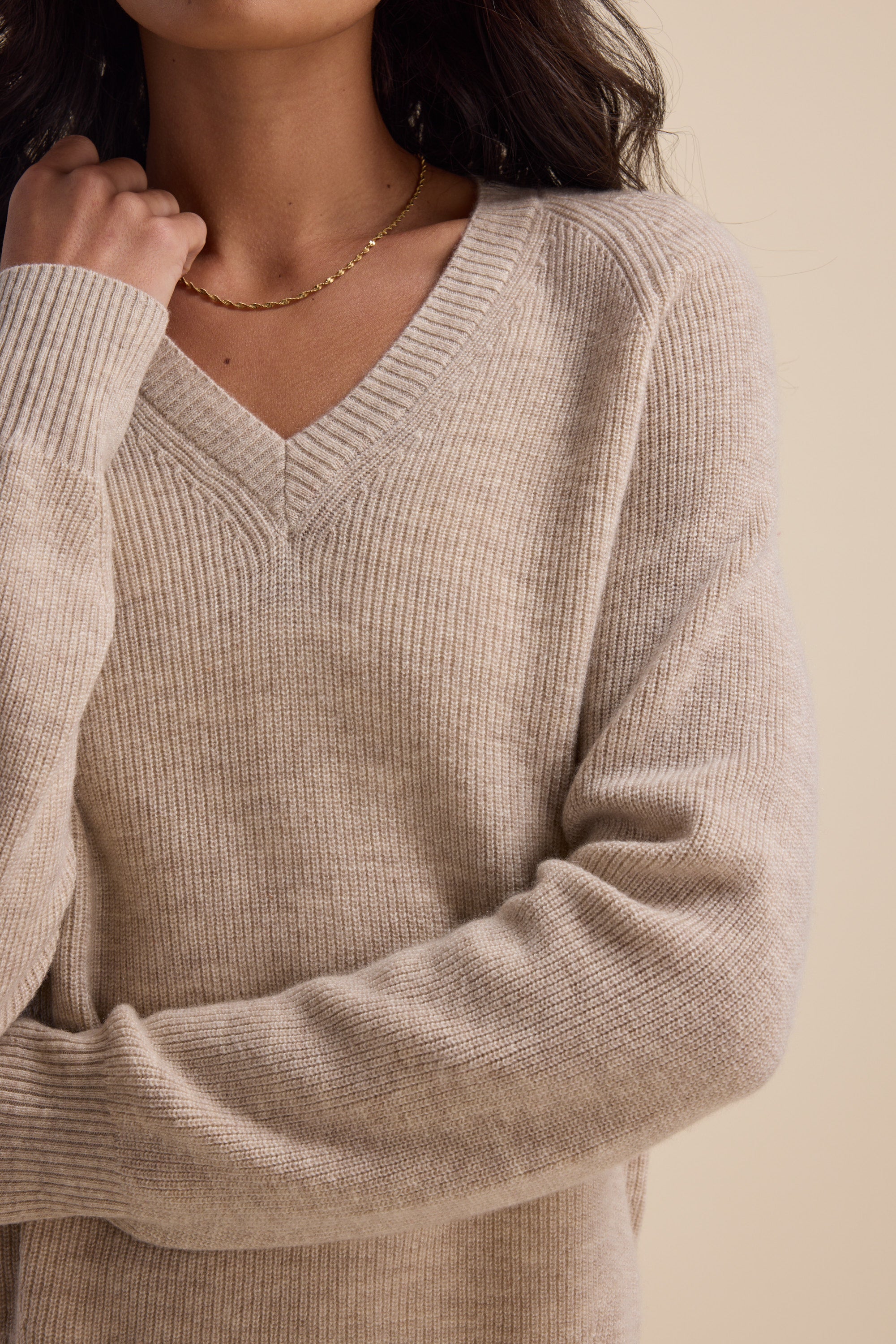 Woman in an Elementary Cashmere Blend V Neck Sweater and a thin gold necklace.