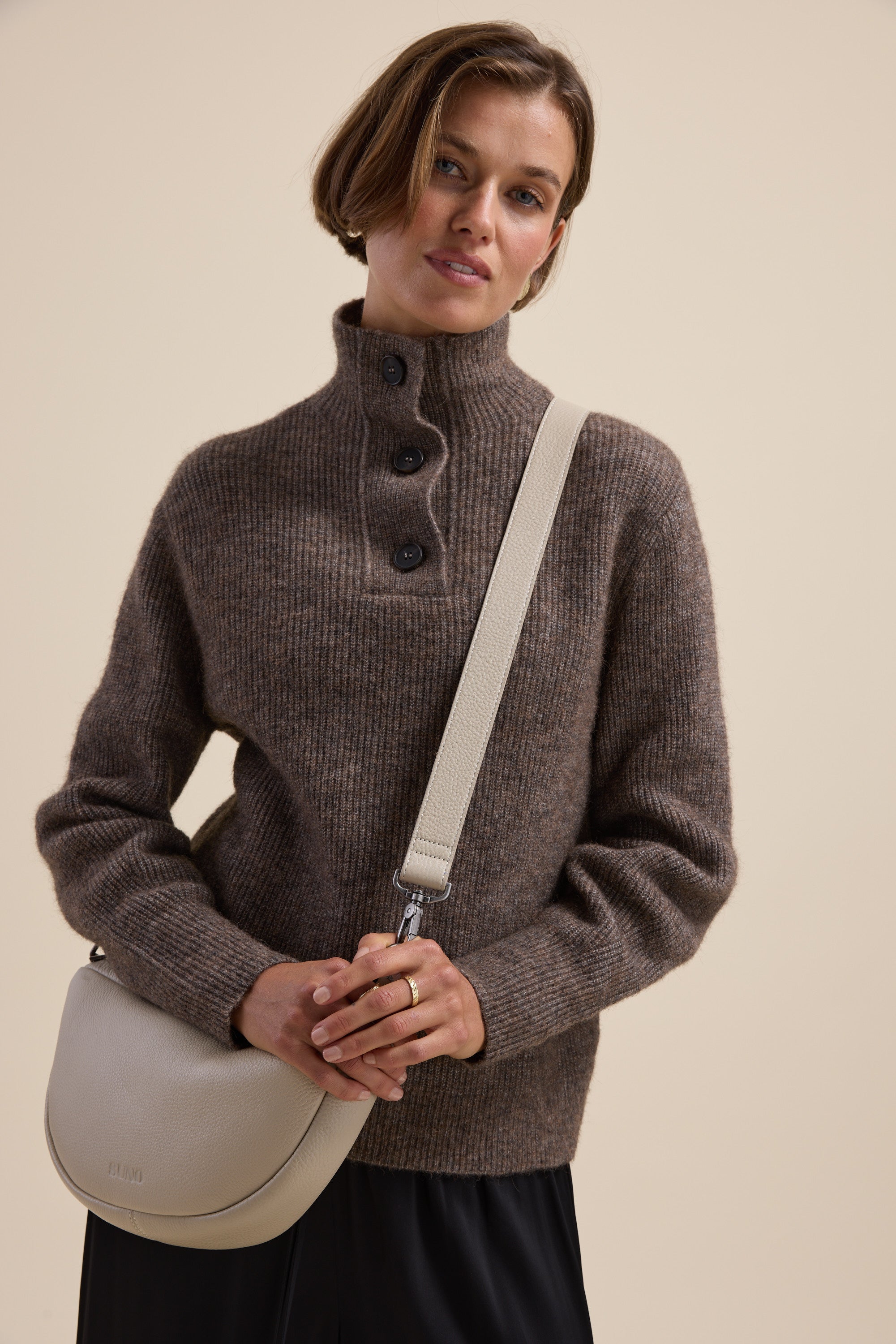 Woman in an Elementary relaxed fit collar detail sweater, holding a light beige crossbody bag.