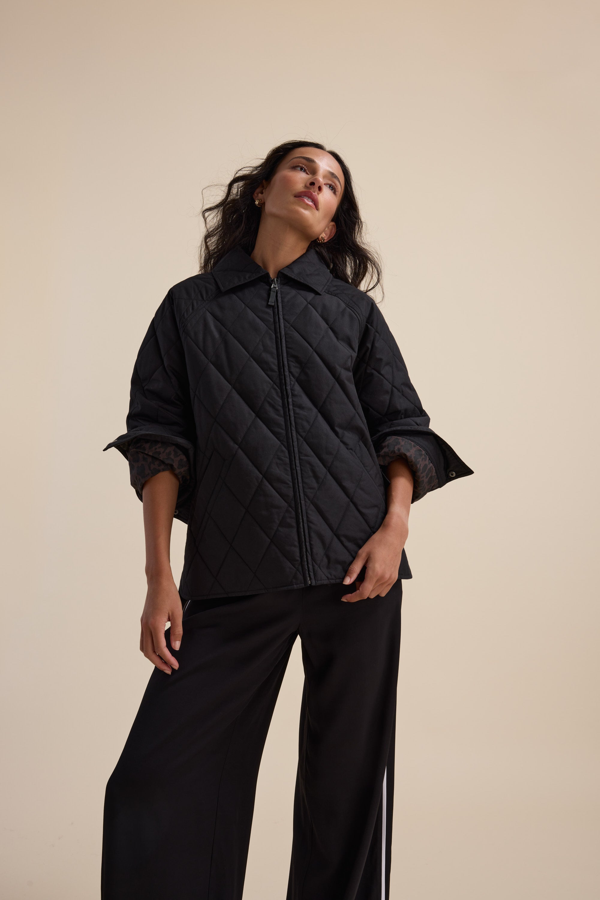Woman wears the Elementary Quilted Puffer by Elementary, posing against a beige background.