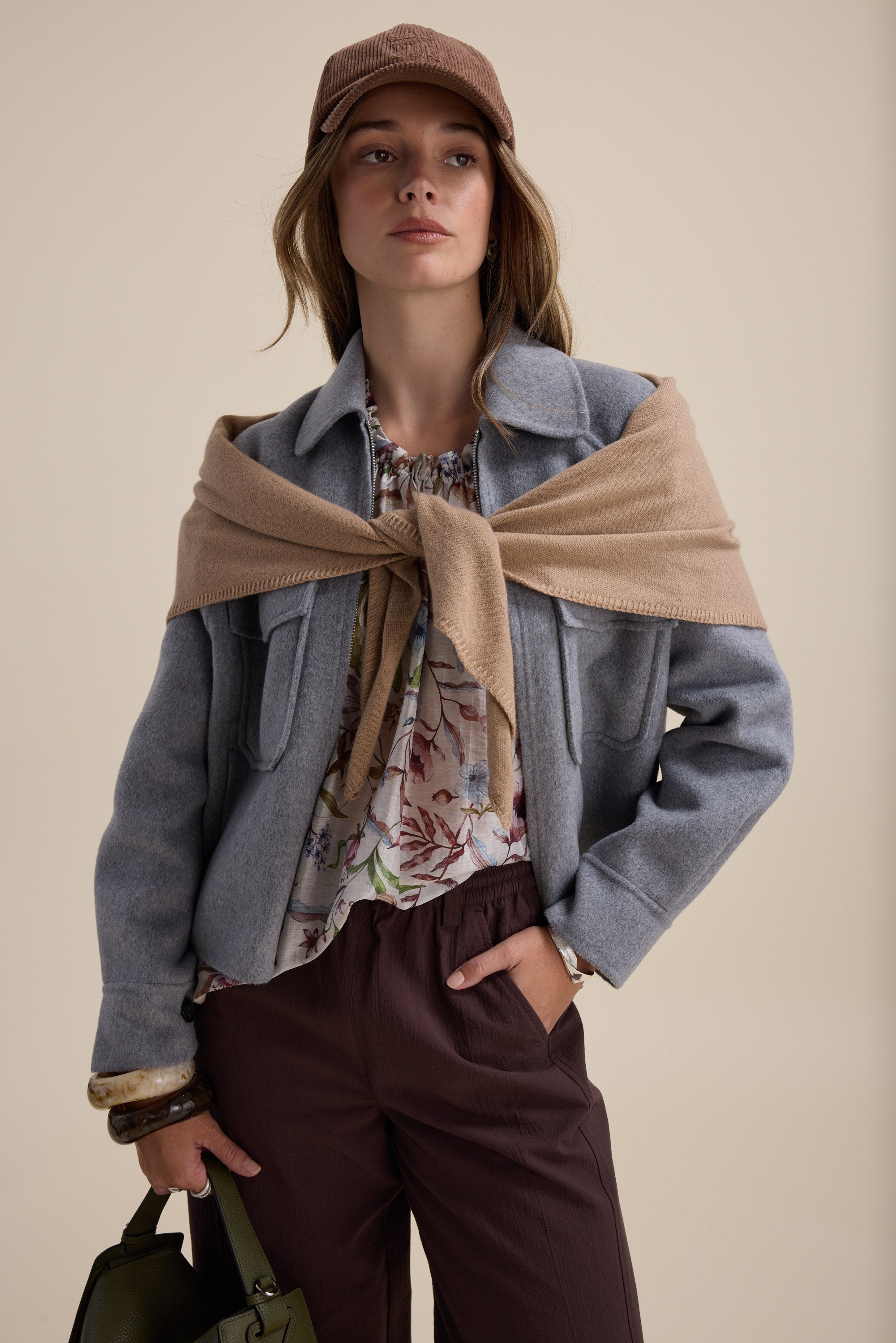 Woman in a gray jacket, brown pants, cap, and Max Quinn Gather Detail Blouse on her shoulders.