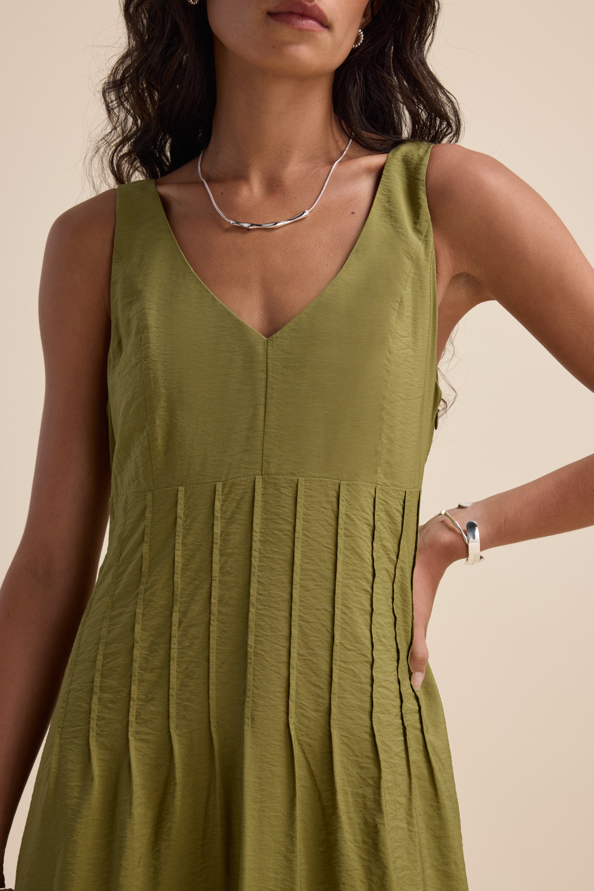 Woman wearing Max's Nina Fit and Flare Dress in dill green, with silver necklace and bracelet.