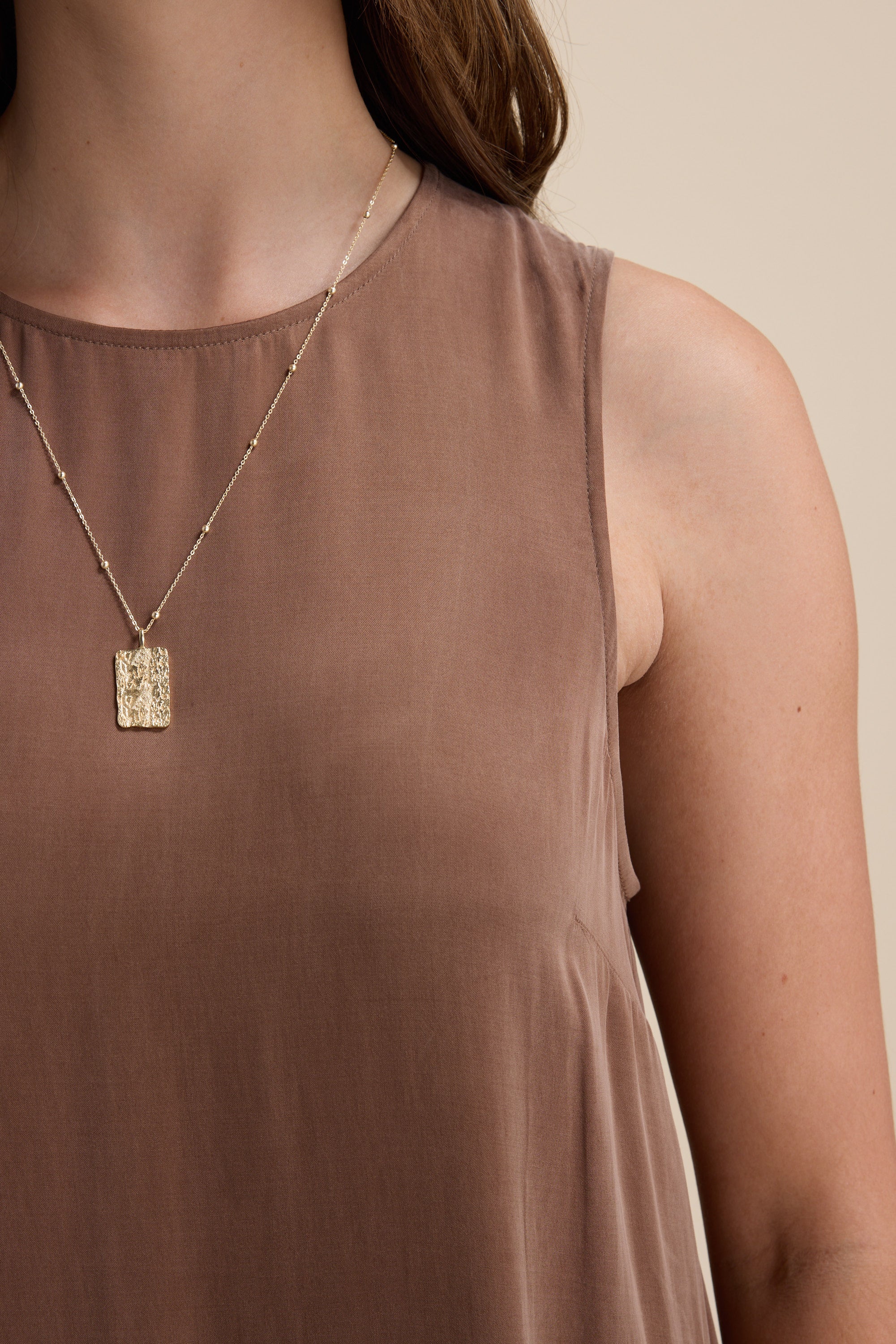 Woman in Max Kaitlyn Flared Midi Dress and gold rectangular pendant necklace.
