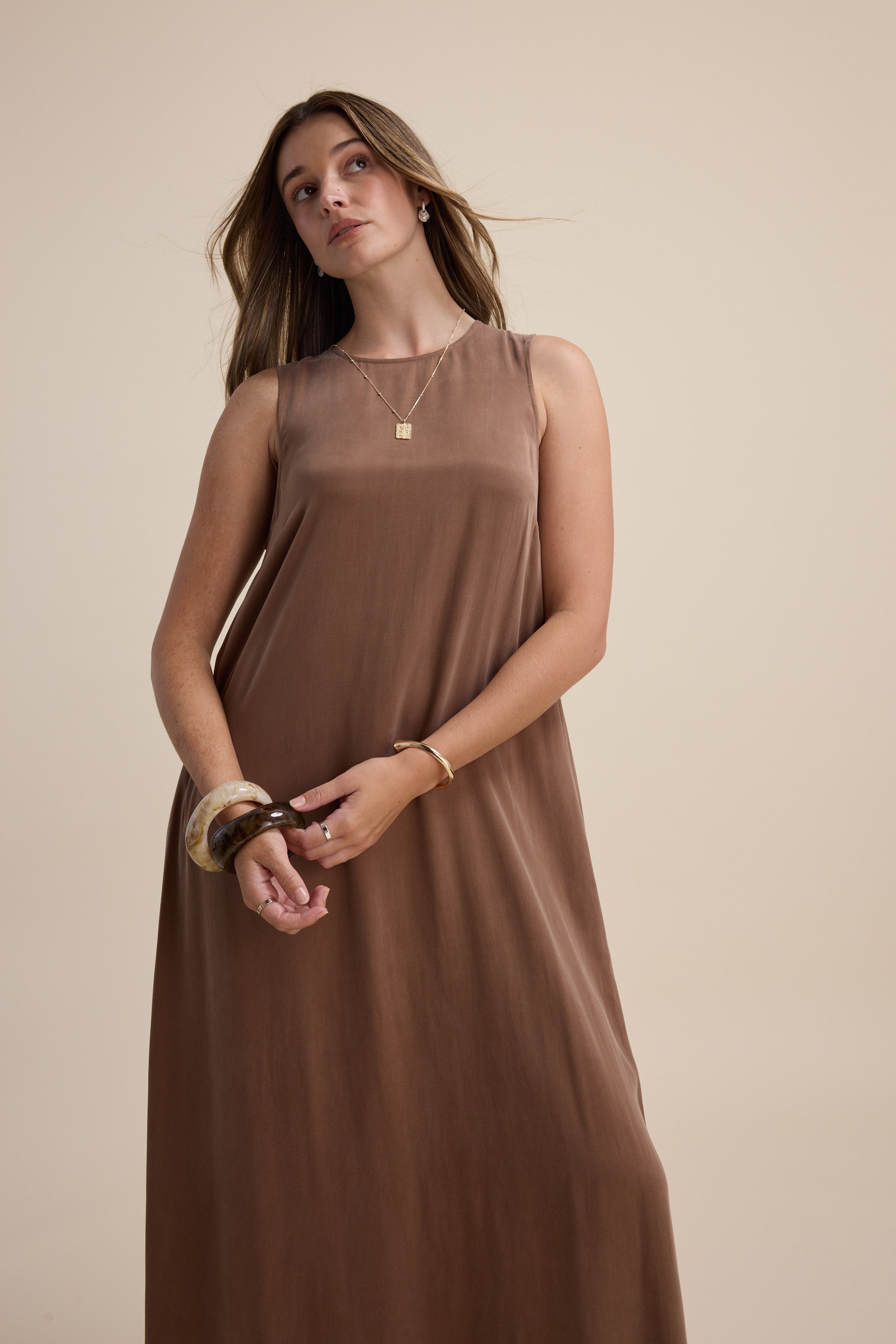 Woman in the Kaitlyn Flared Midi Dress by Max, posing against a beige background.