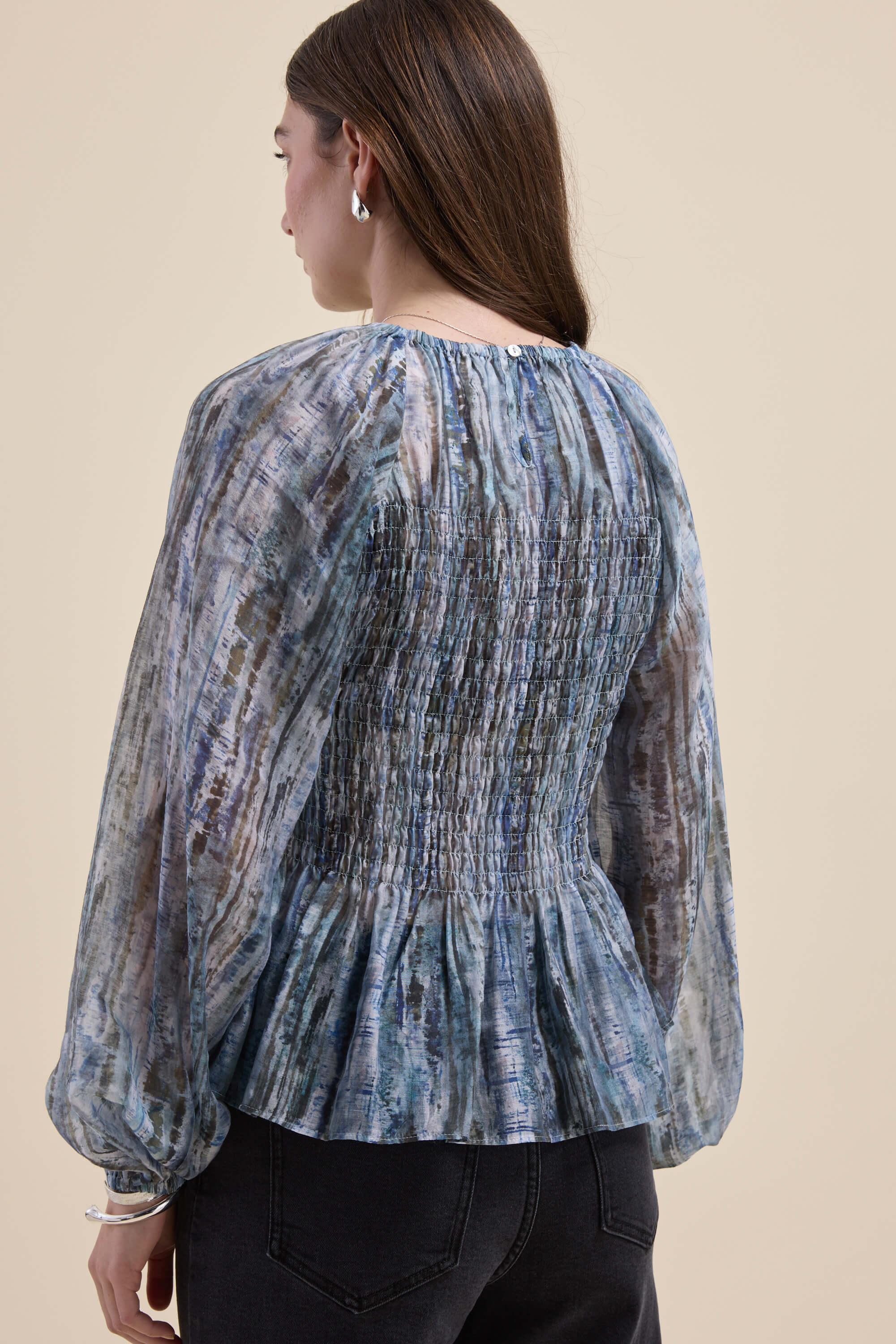 Woman in the Max Mitch Shirred Top, blue patterned with long sleeves, seen from the back.