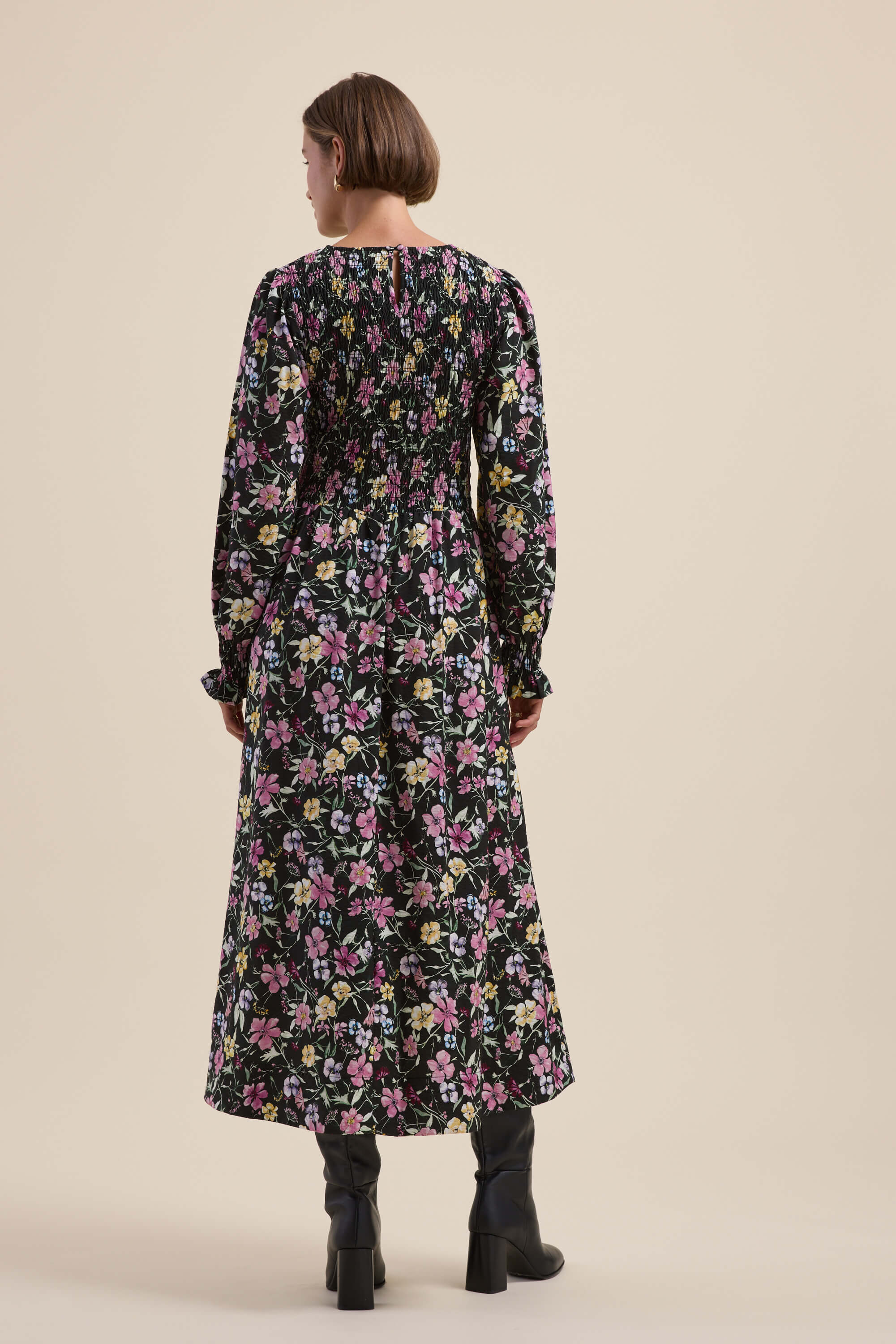 Woman in a Max Brooke Shirred Long Sleeve Dress and black boots, shown from the back.
