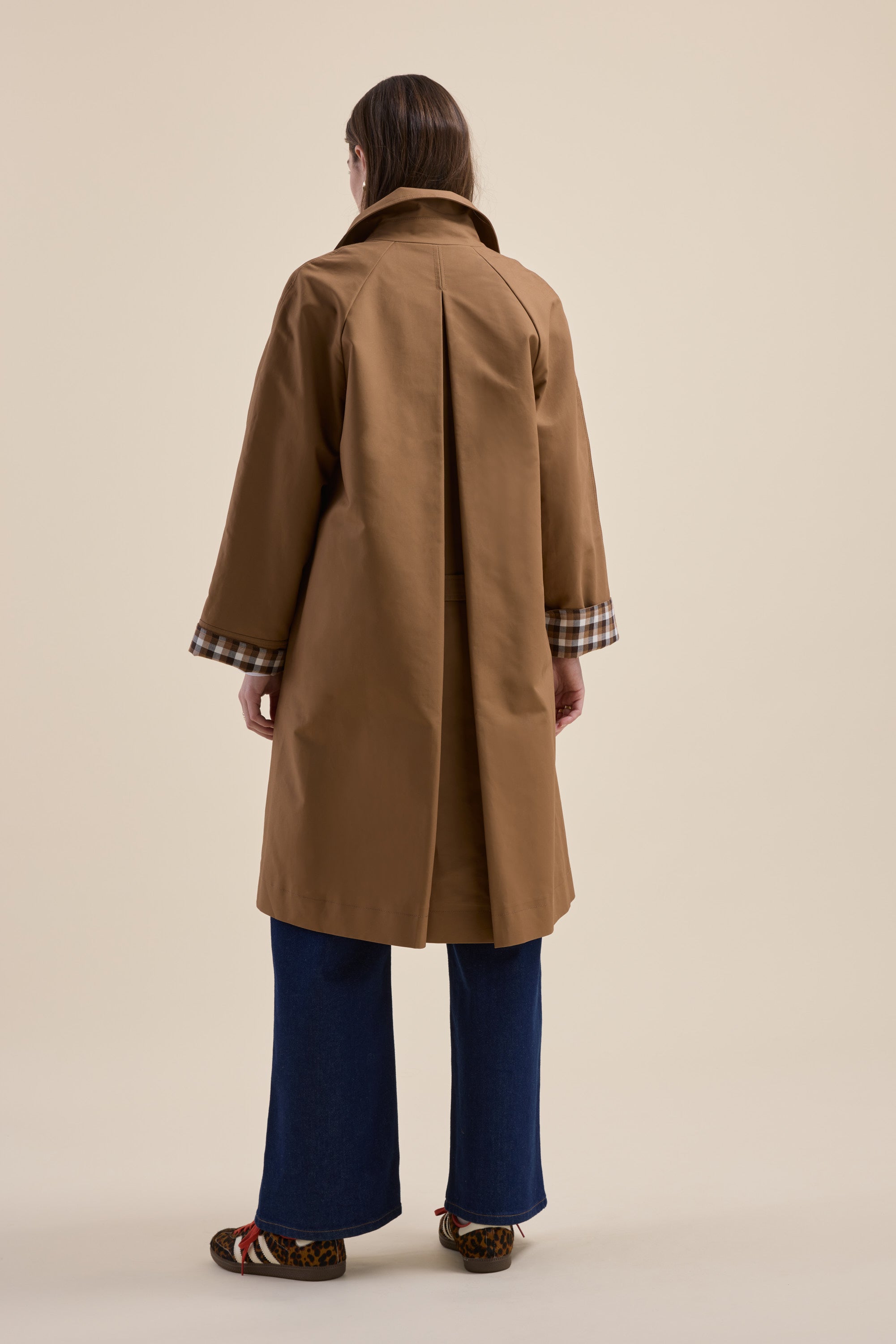 Person in a Max London Trench Coat, blue jeans, and patterned shoes, facing away.