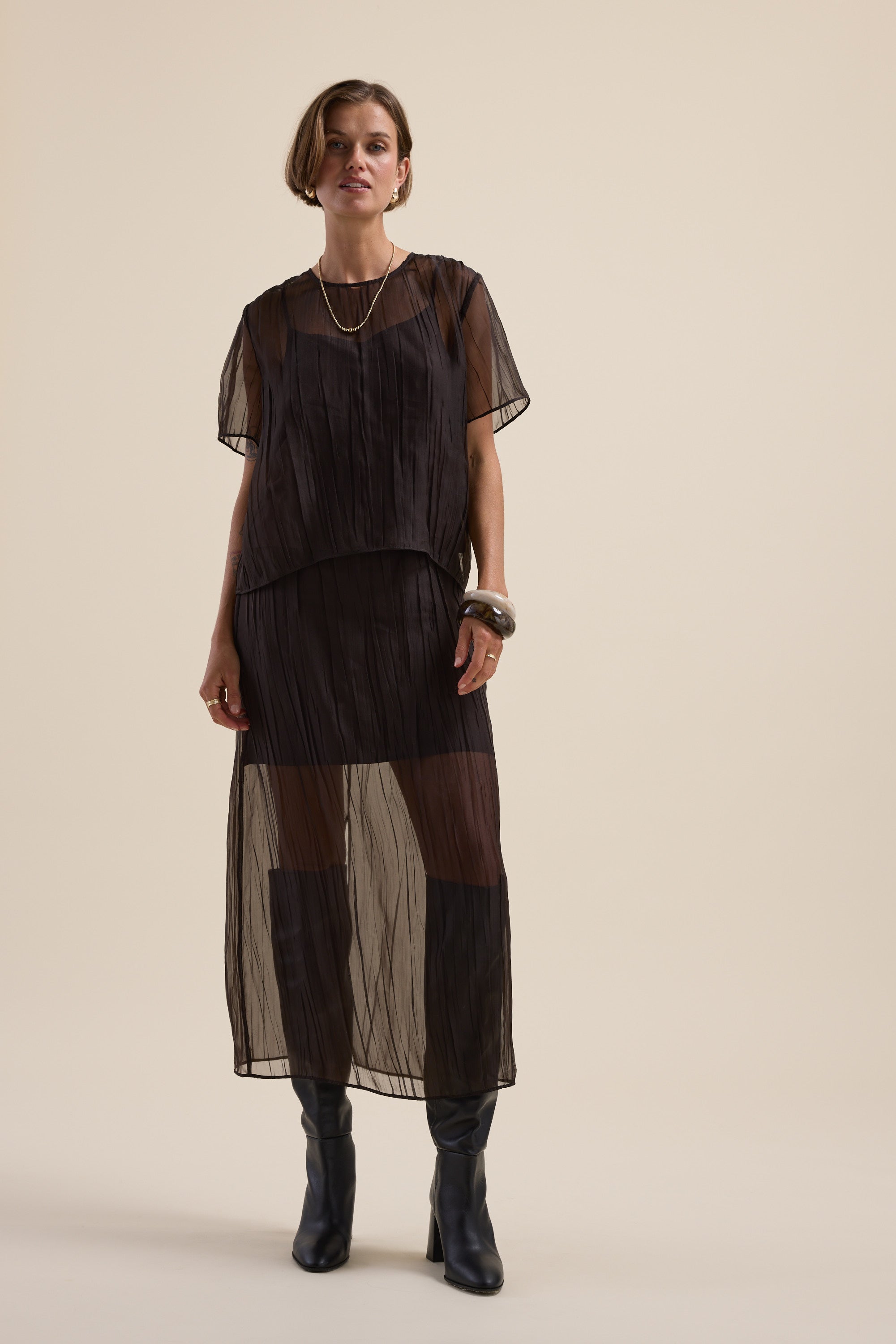 Woman in Ari Sheer Midi Skirt by Max, styled with boots—ideal for special occasions.