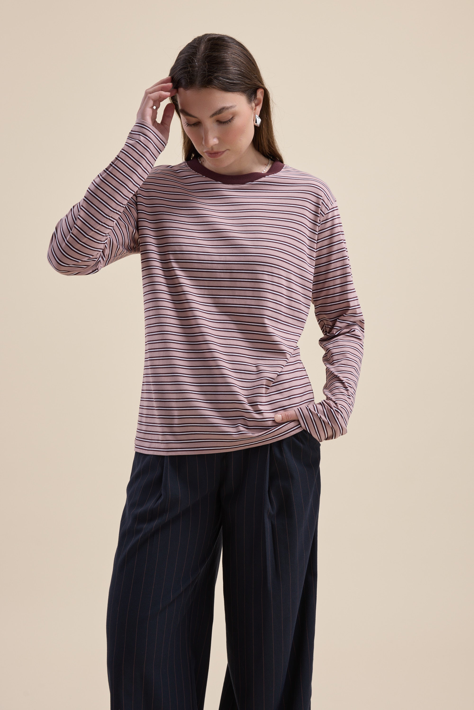 Woman in Max Carmen Long Sleeve Stripe Tee and dark pinstriped pants, looking down.
