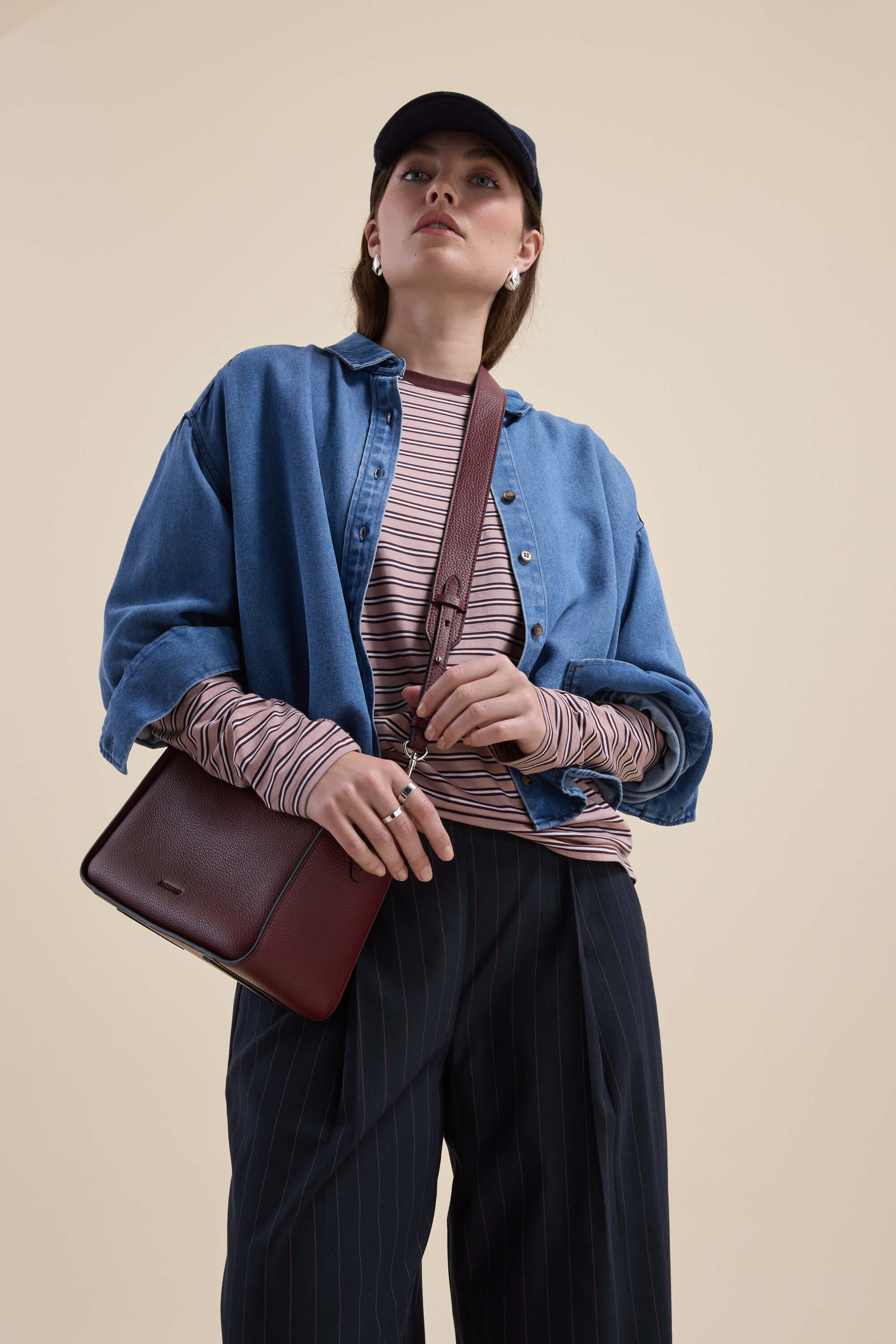 Person in casual outfit wearing Max Carmen Long Sleeve Stripe Tee, denim shirt, black pants, maroon bag.