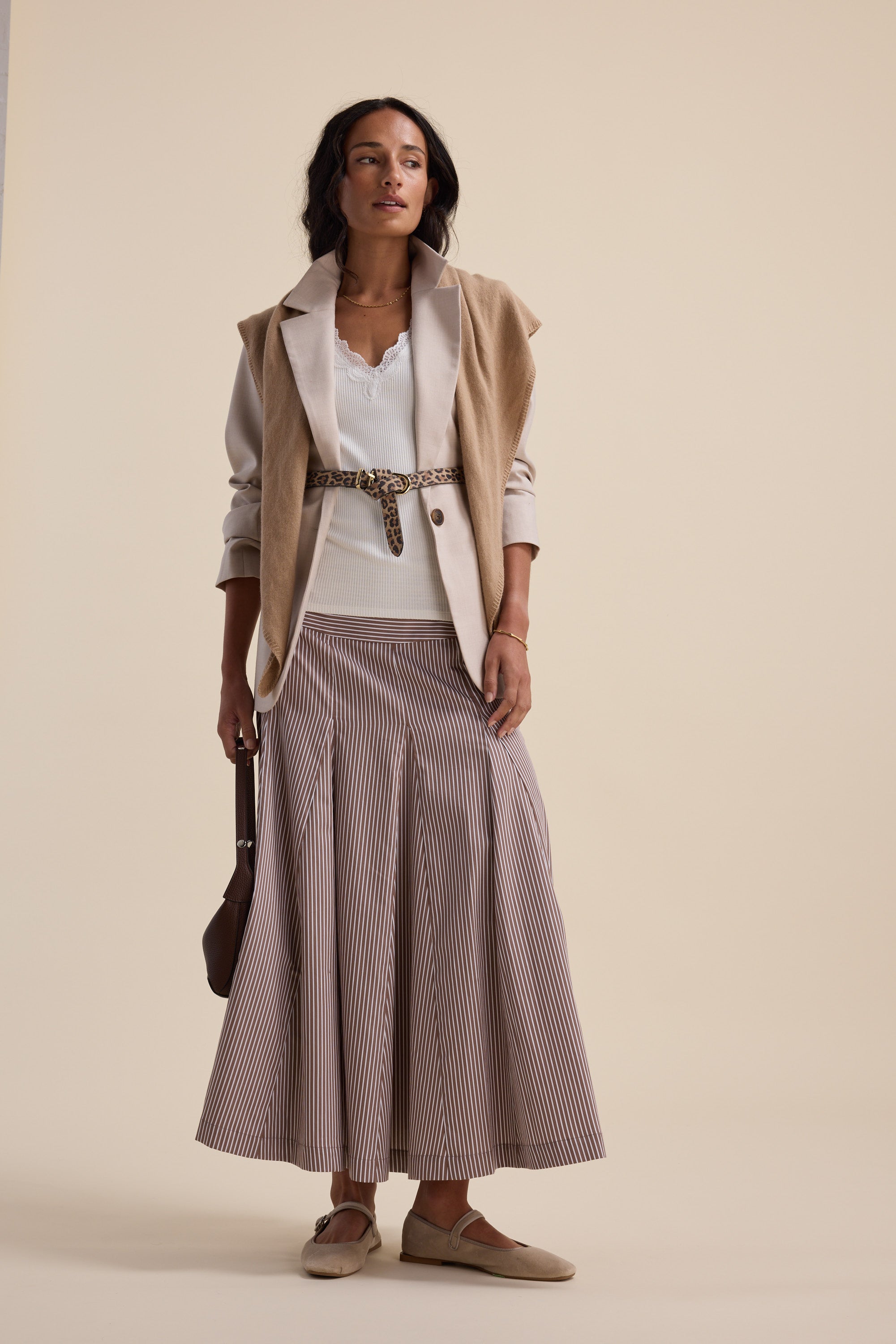 Woman in Aubree Lace Trim Tank by Max, beige vest, striped skirt, loafers, holding brown bag.