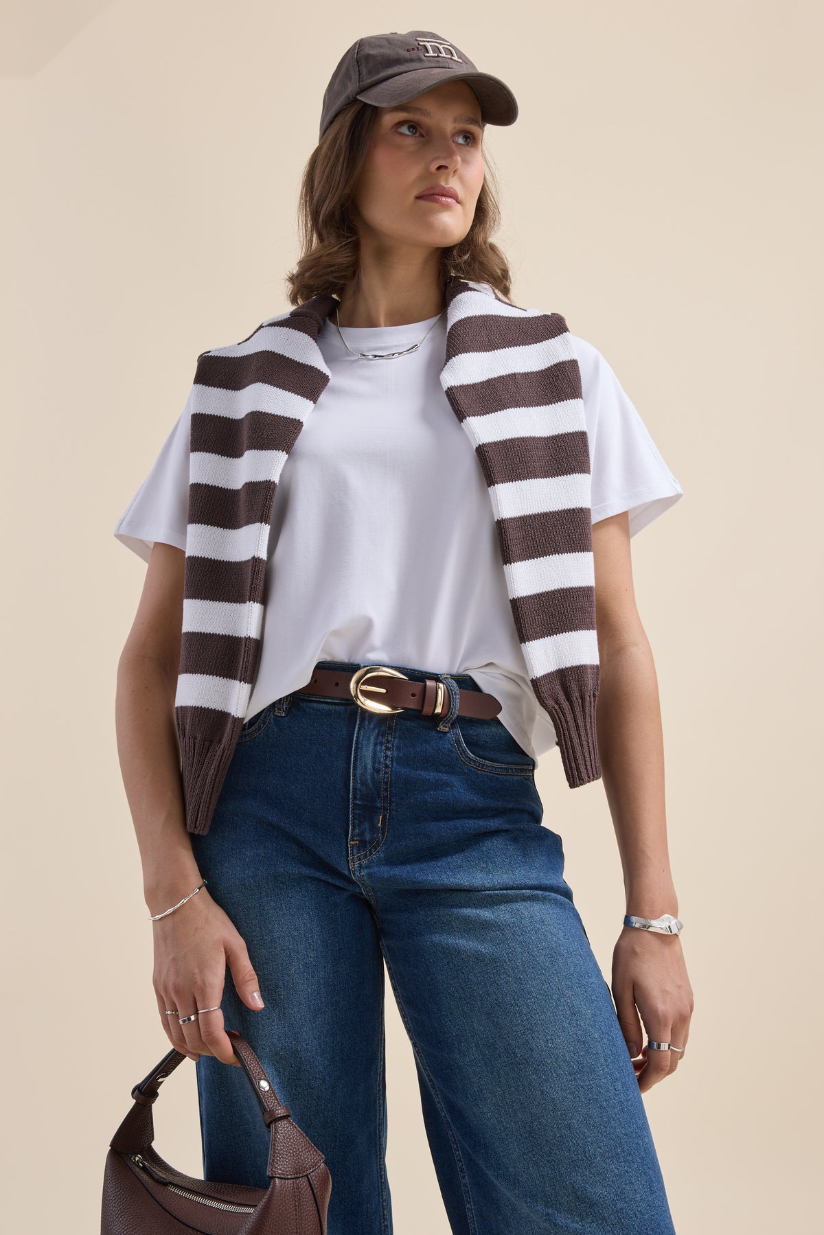 Woman in casual look: Elementary Slouchy Short Sleeve Tee, jeans, cap, brown purse.